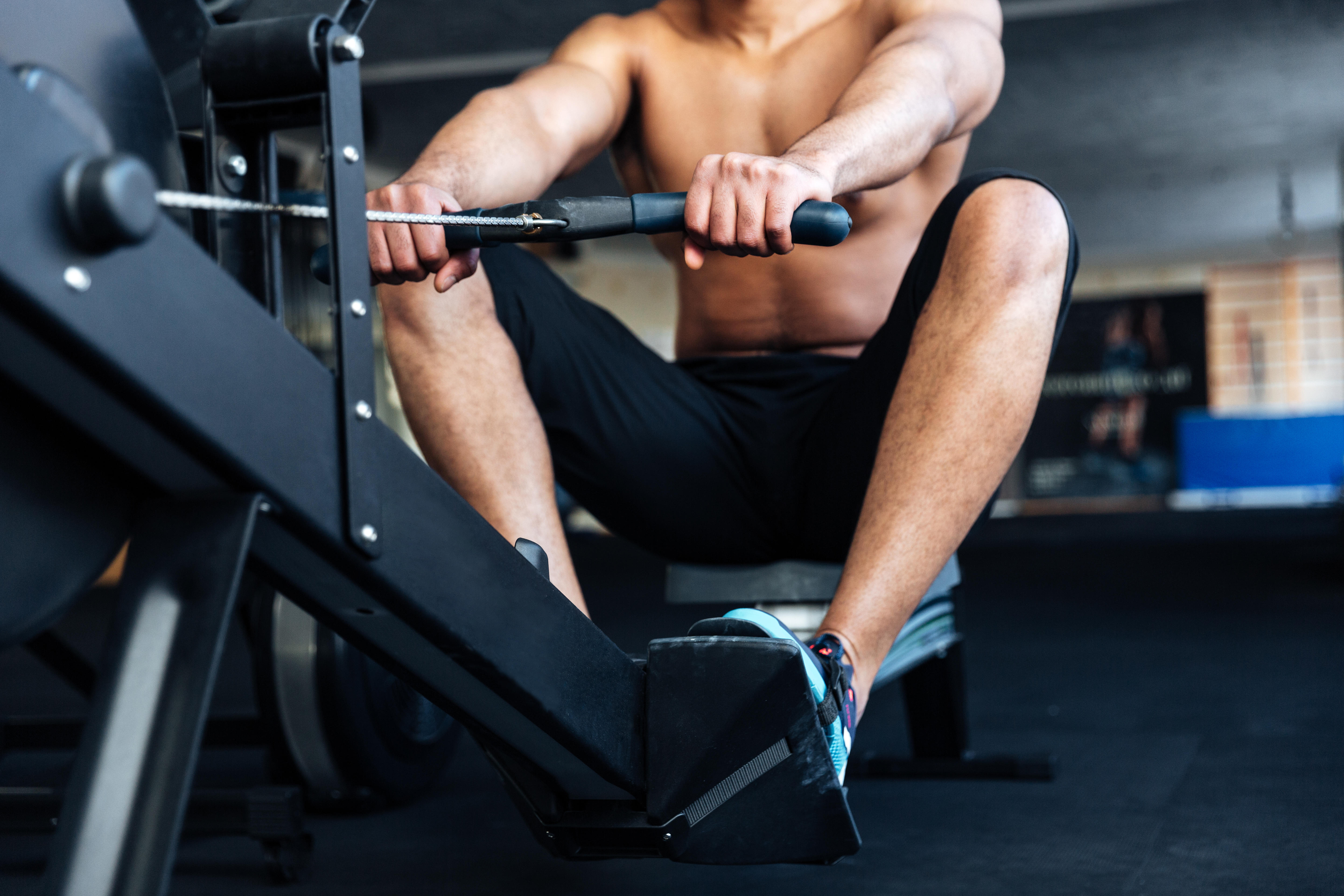 Cropped image of a fitness man using rowing machine in the gym