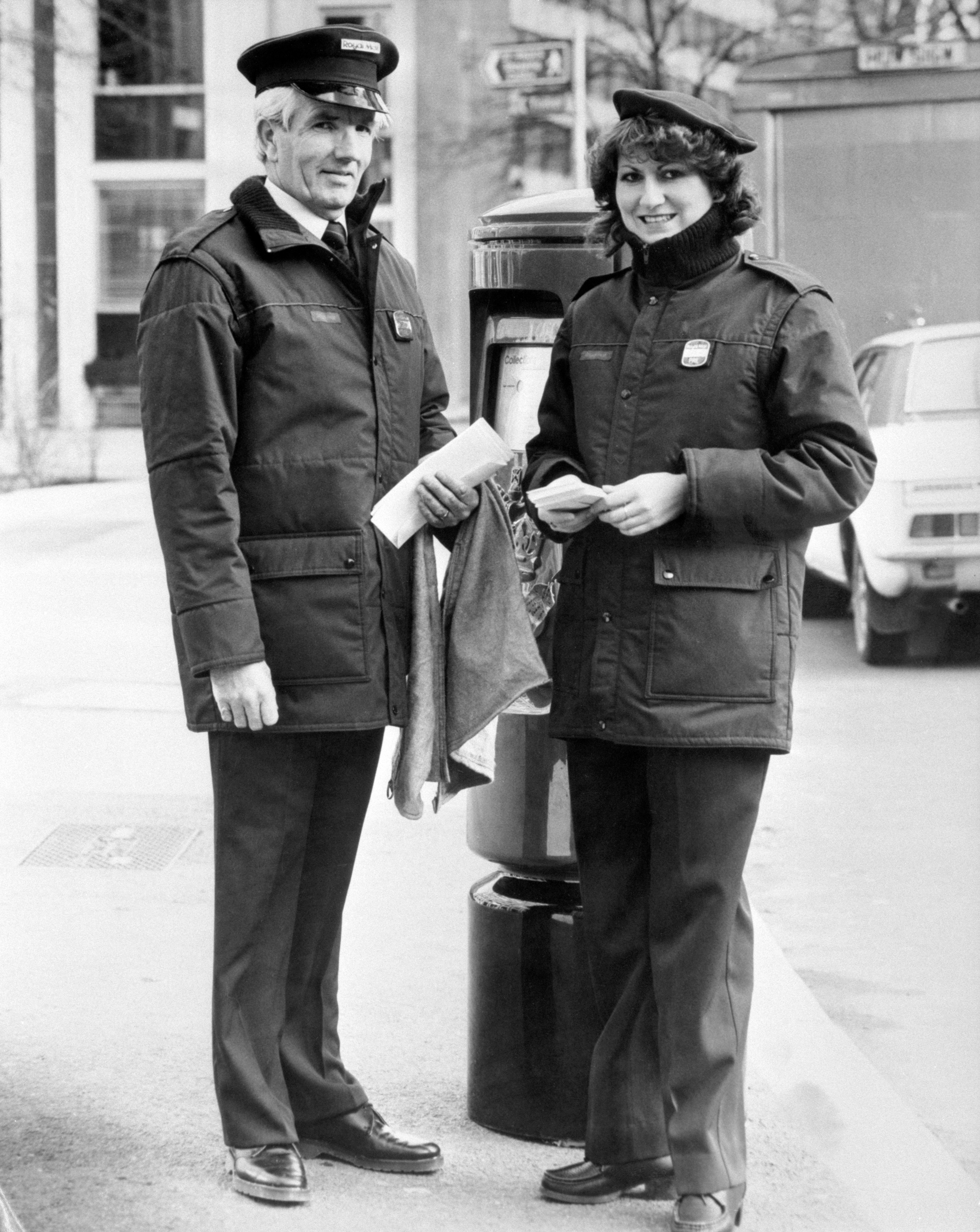 Two postal workers model the latest dresswear for winter weather