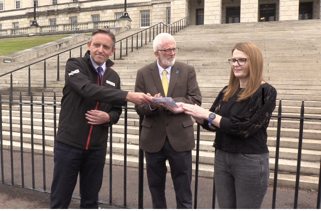 Travel agent Damien Murphy hands a letter to Caoimhe Archibald, chairwoman of Stormont's Economy Committee
