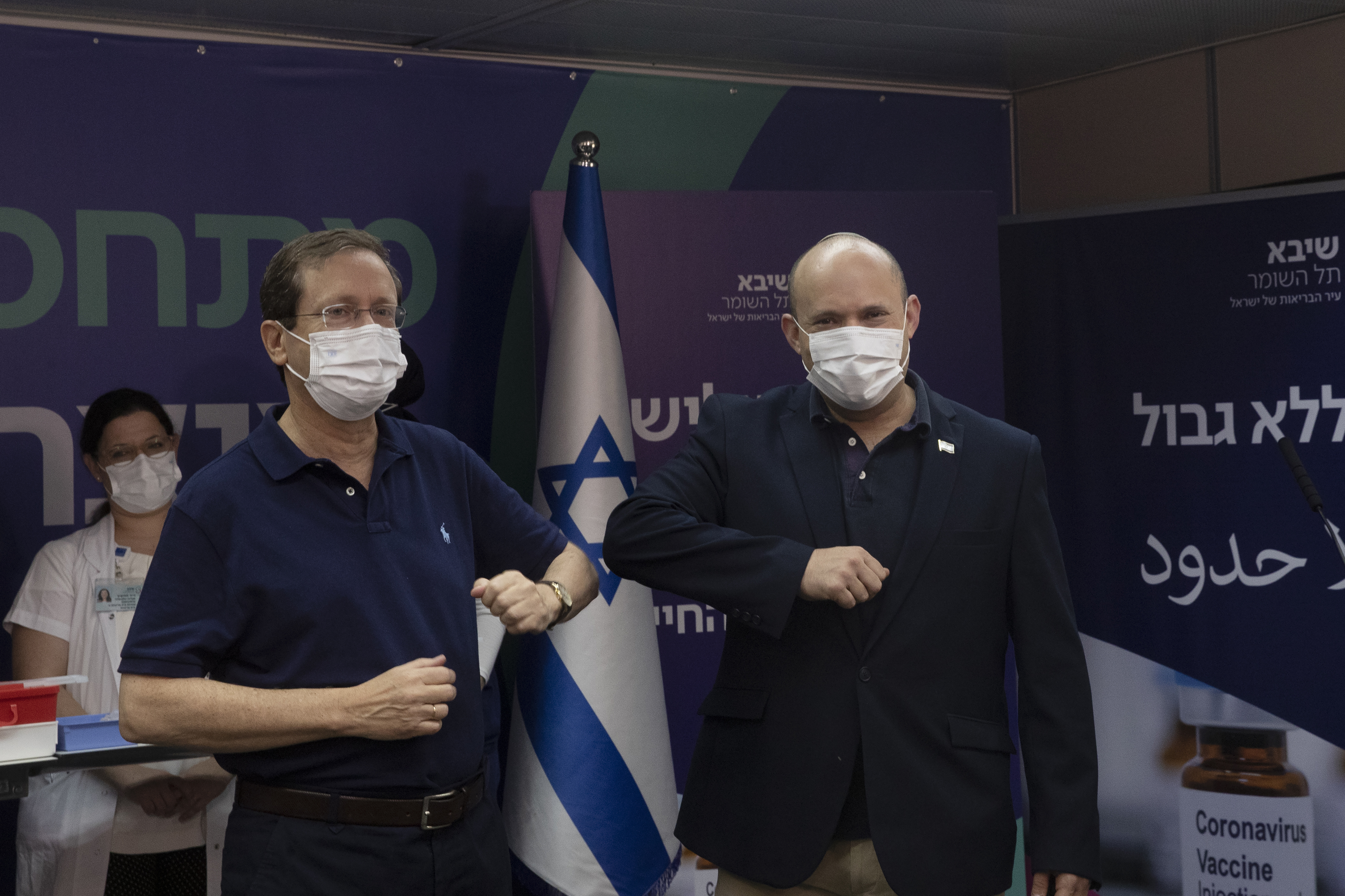 Israeli president Isaac Herzog, left, bumps elbows with prime minister Naftali Bennett after receiving his booster jab 
