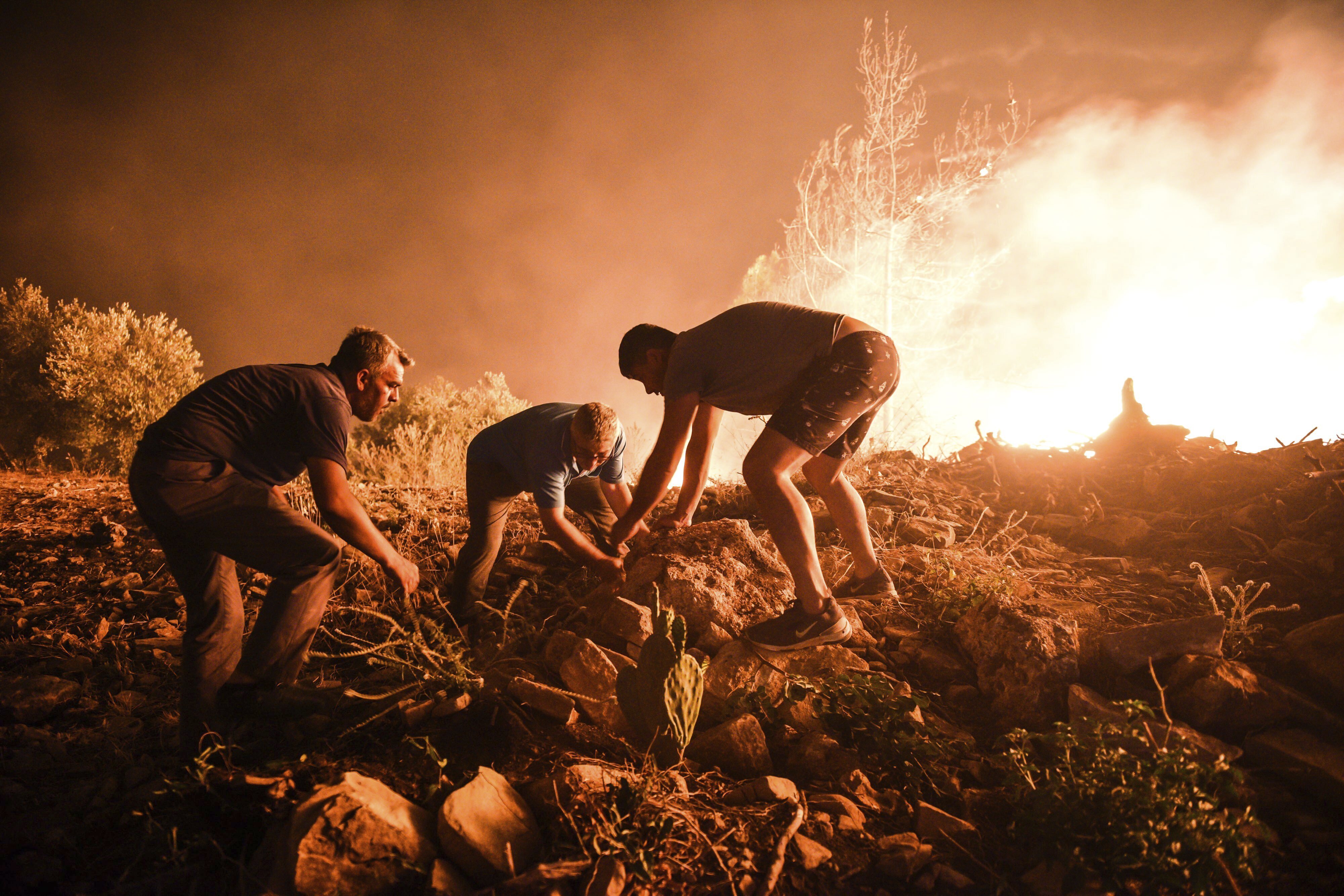 Villagers attempt to bring a fire in Kirli village, in Antalya province, under control 