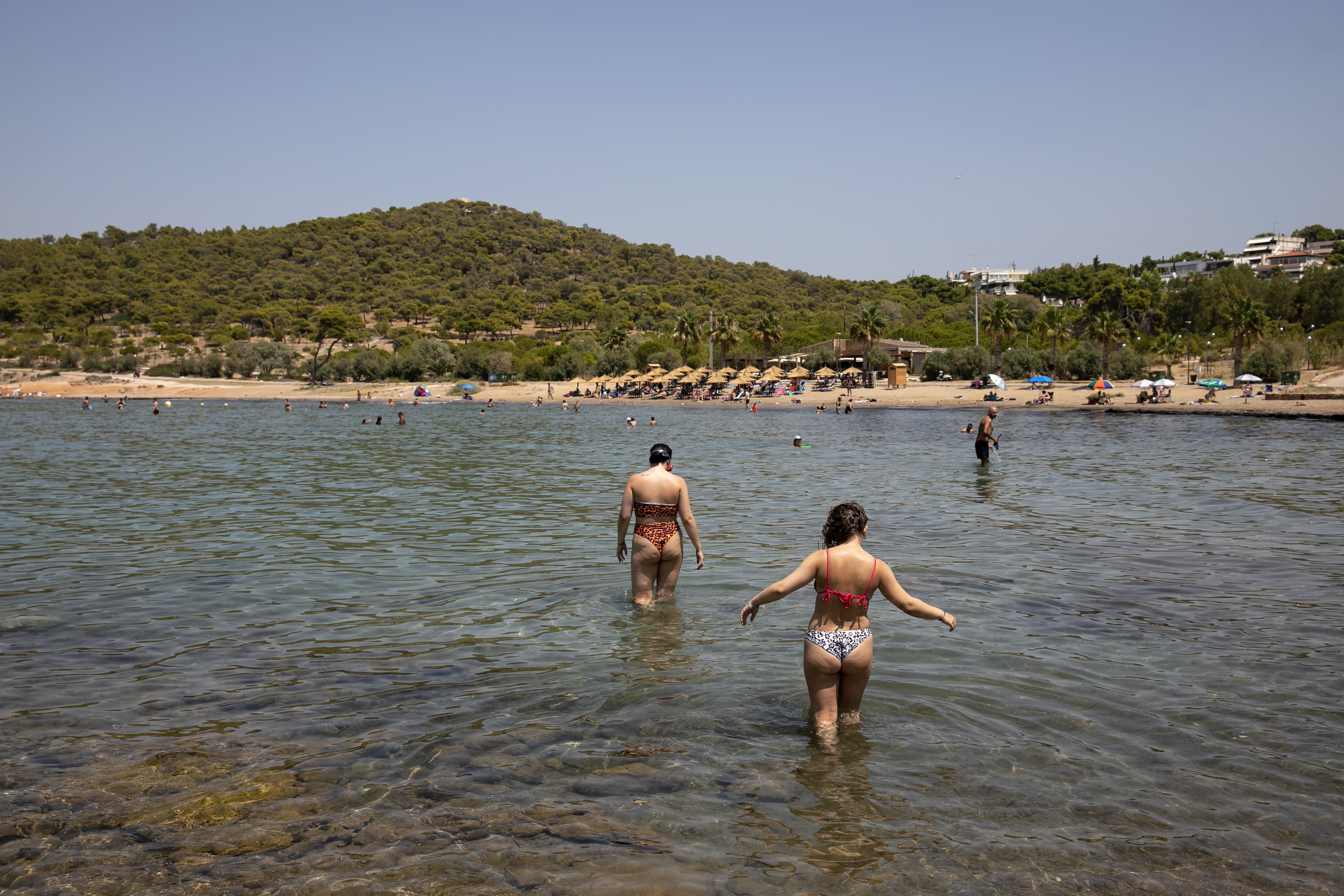 Swimmers walk into the sea at a beach of Kavouri suburb, south-west of Athens