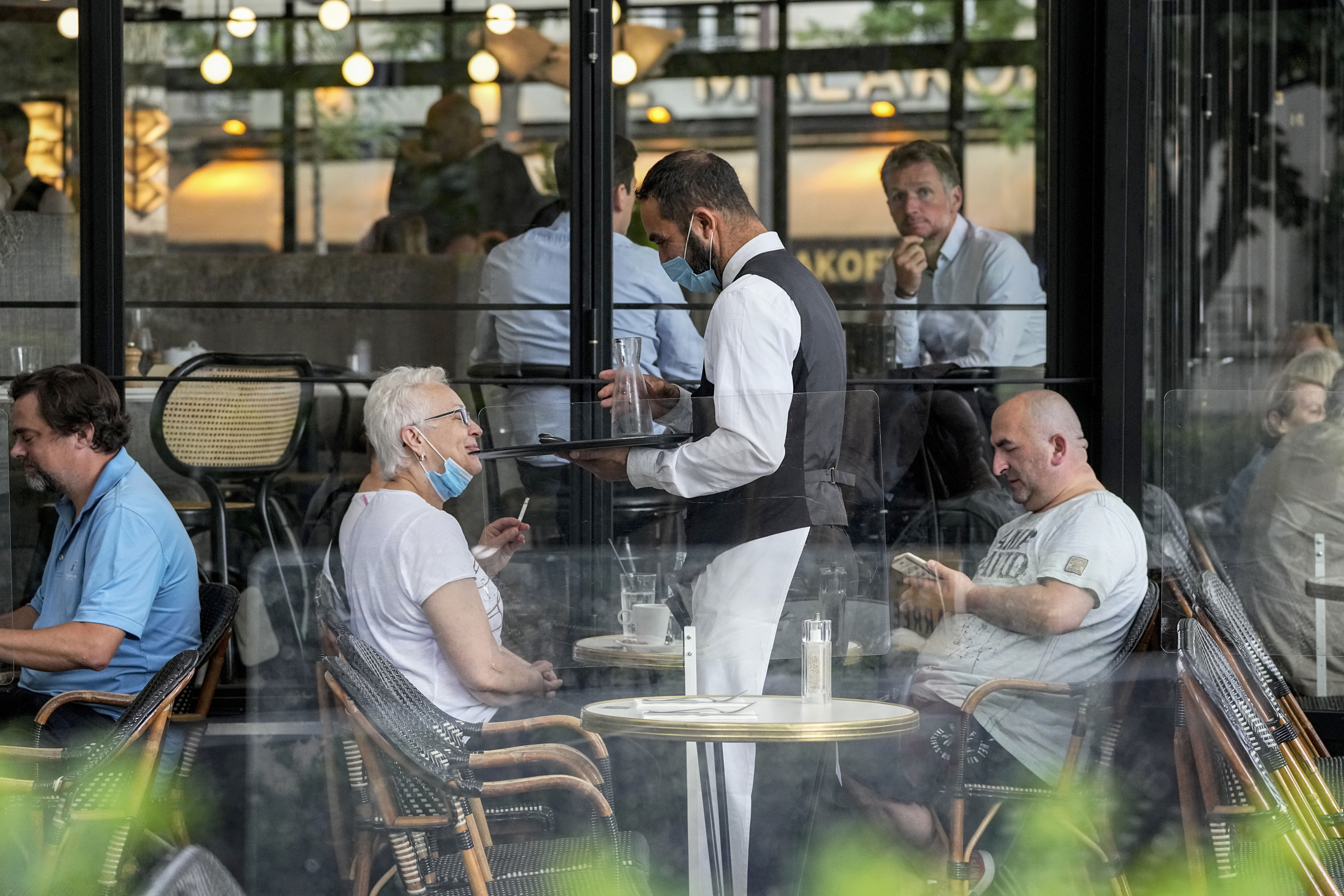 A waiter wearing a face mask serves customers at a restaurant in Paris 
