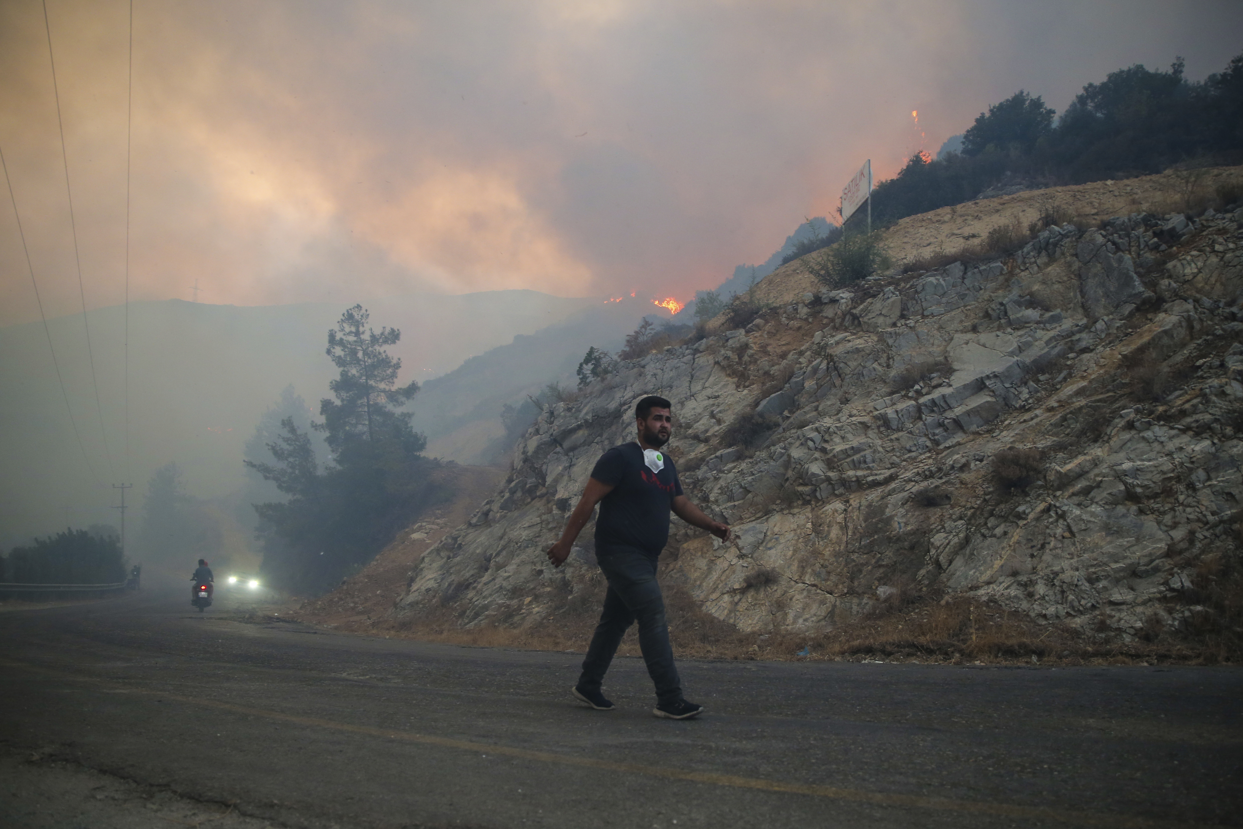 A man walks as the blaze approaches in Milas