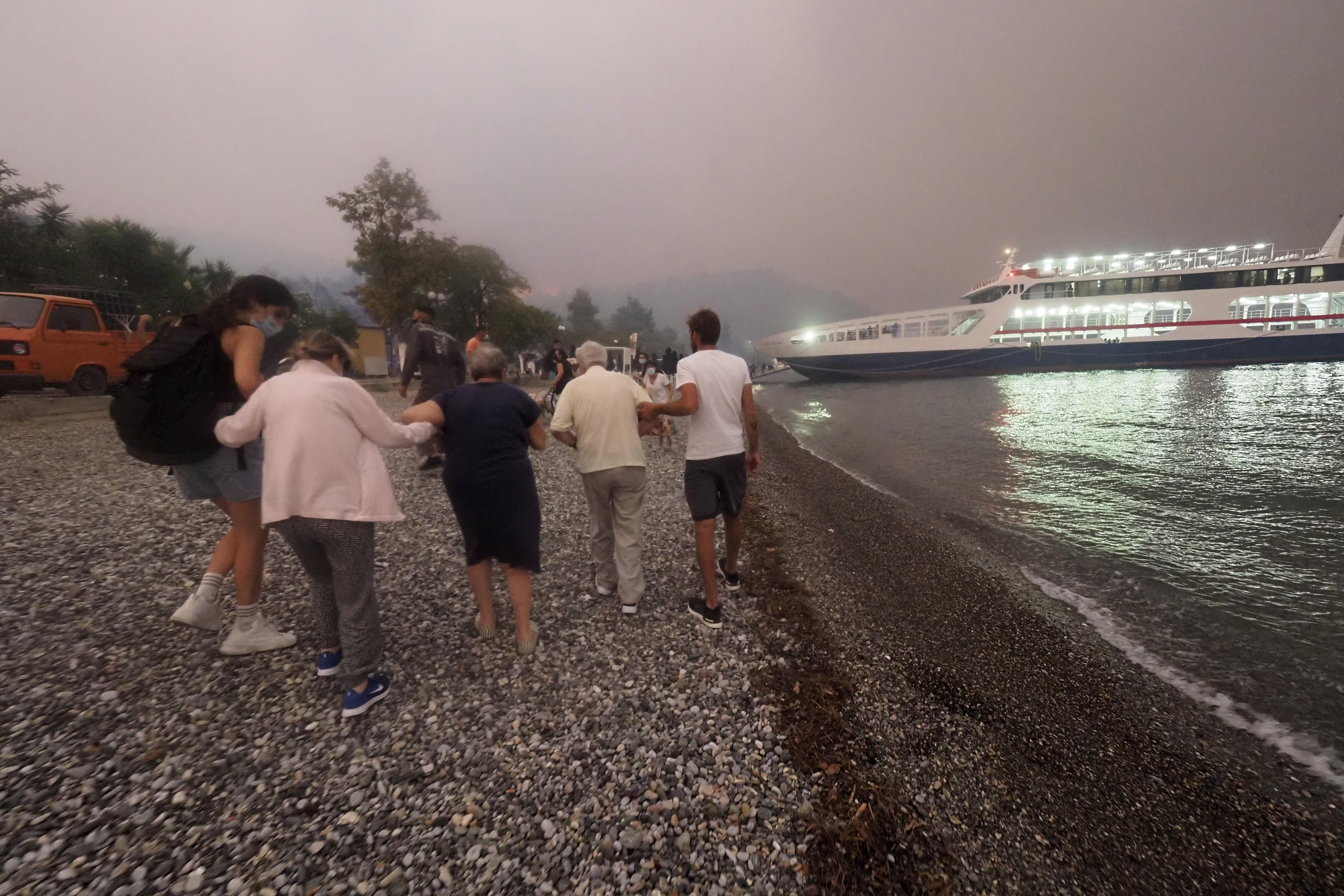 People embark a ferry during an evacuation from Kochyli beach (Theodoros Nikolaou/AP)