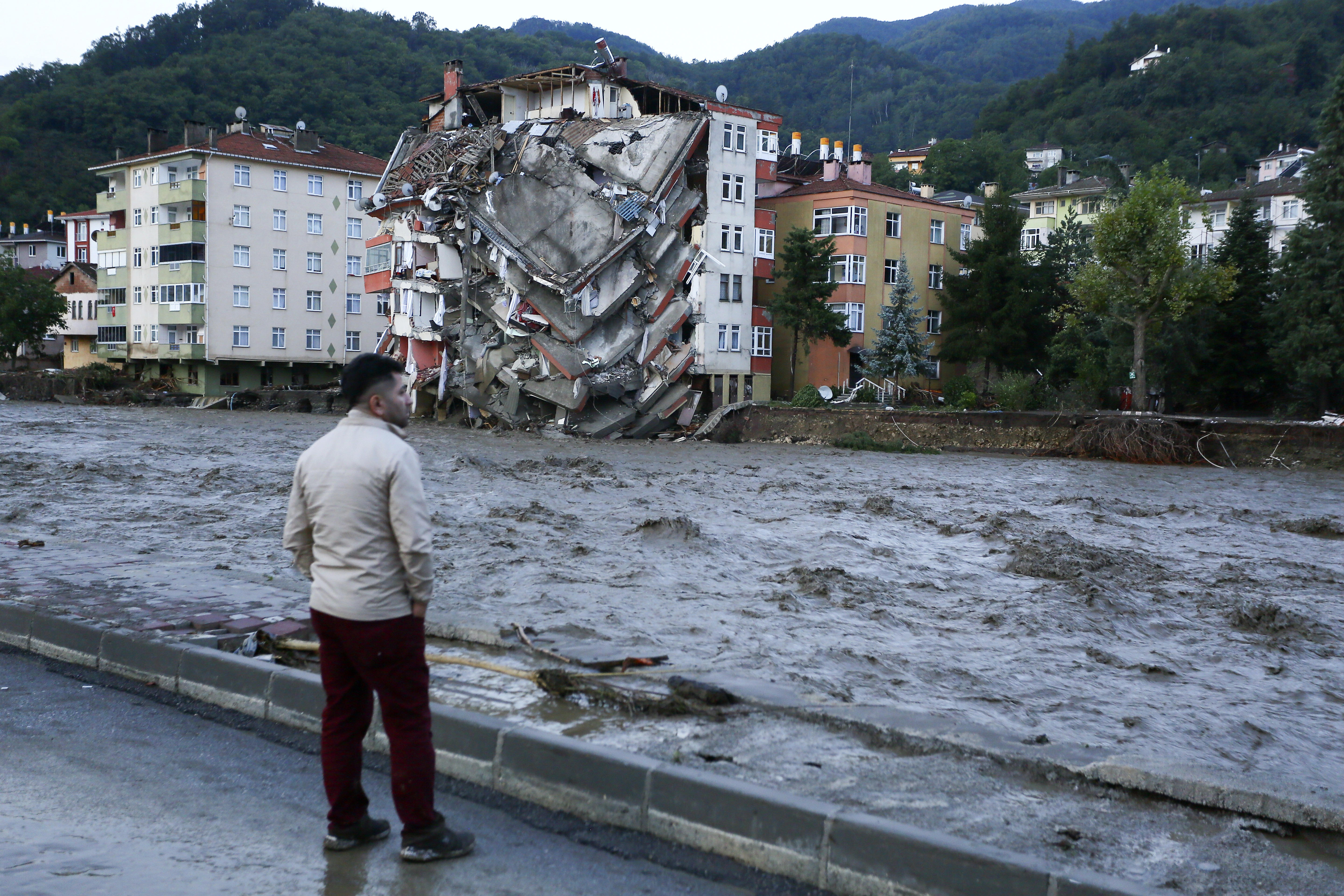 A man looks on as floodwaters sweep by in Bozkurt