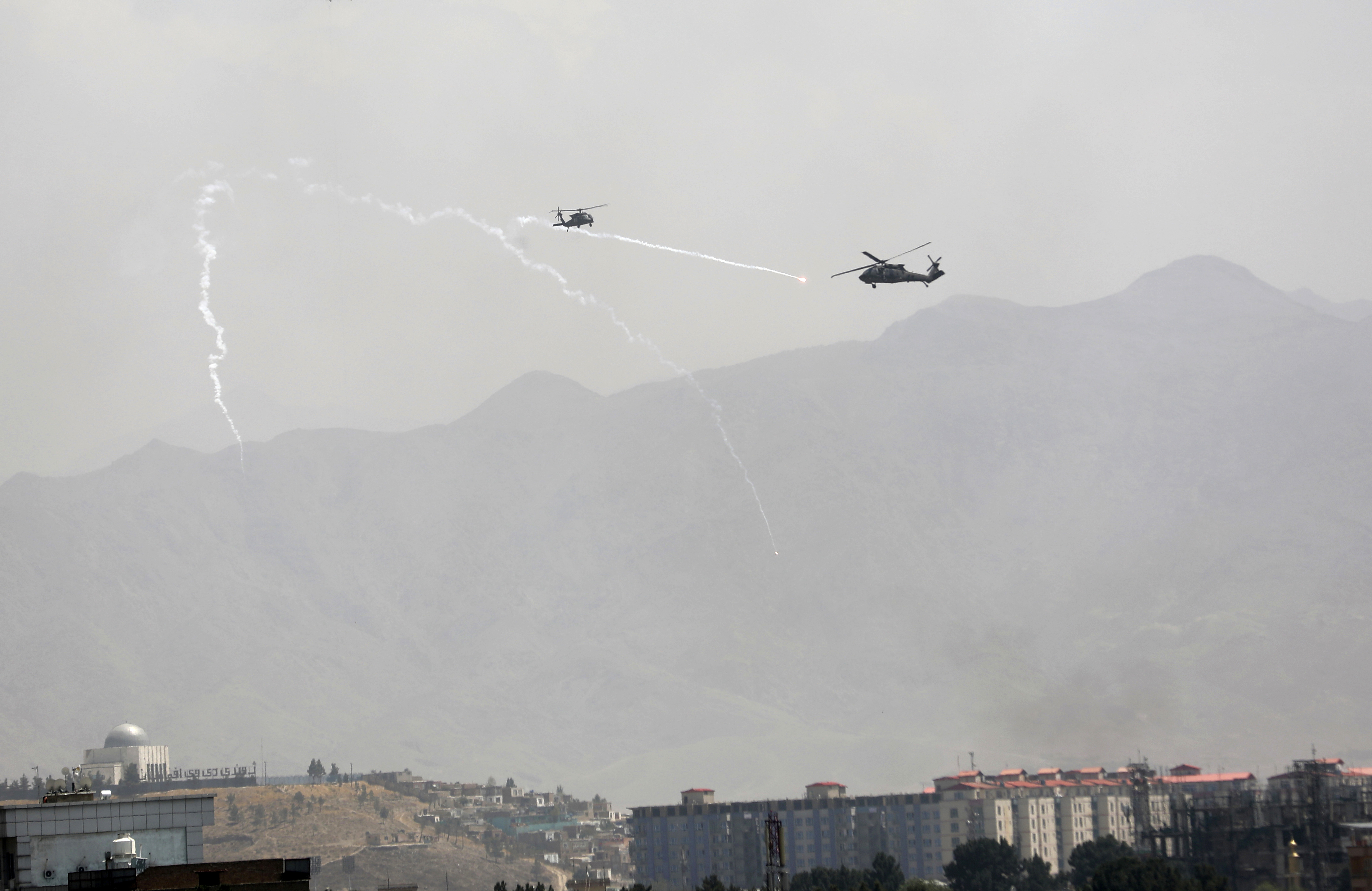 Anti-missile decoy flares are deployed as US Black Hawk military helicopters fly over the city of Kabul, Afghanistan