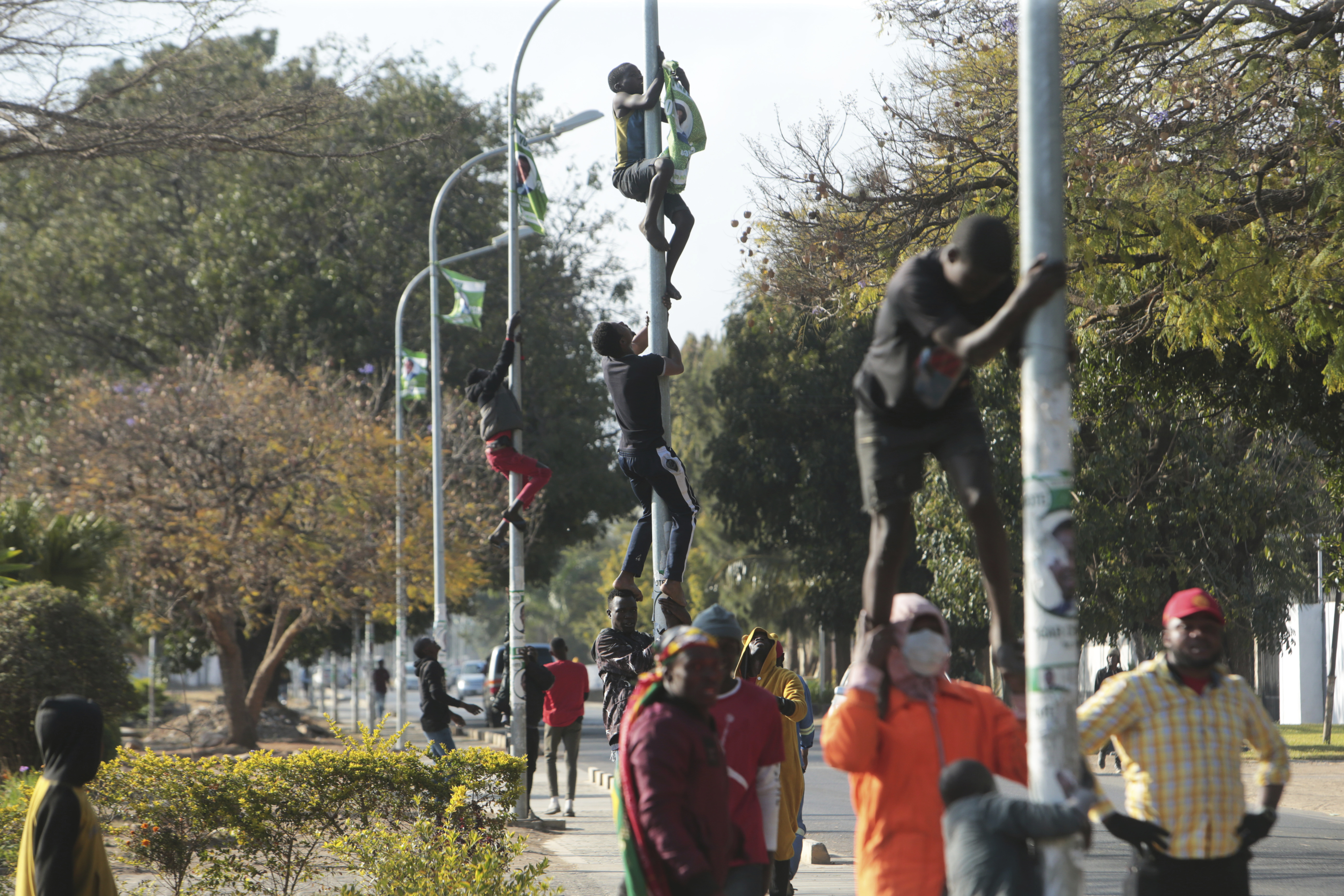 Supporters of Zambian opposition leader Hakainde Hichilema remove campaign posters of Zambian President Edgar Lungu (Tsvangirayi Mukwazhi/AP)