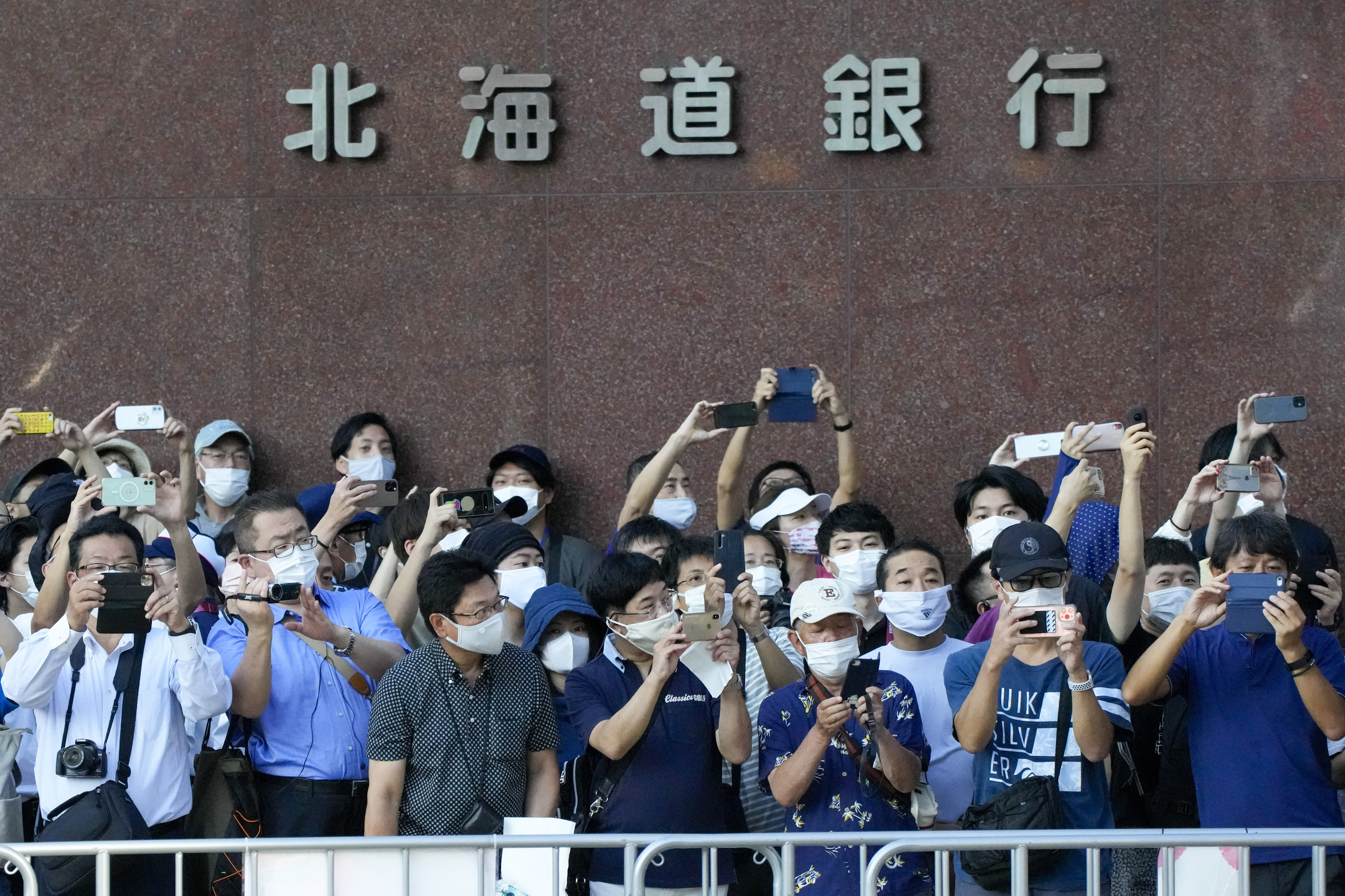 Spectators wearing face masks wait for competitors in the women's marathon at the 2020 Summer Olympics in Sapporo, northern Japan