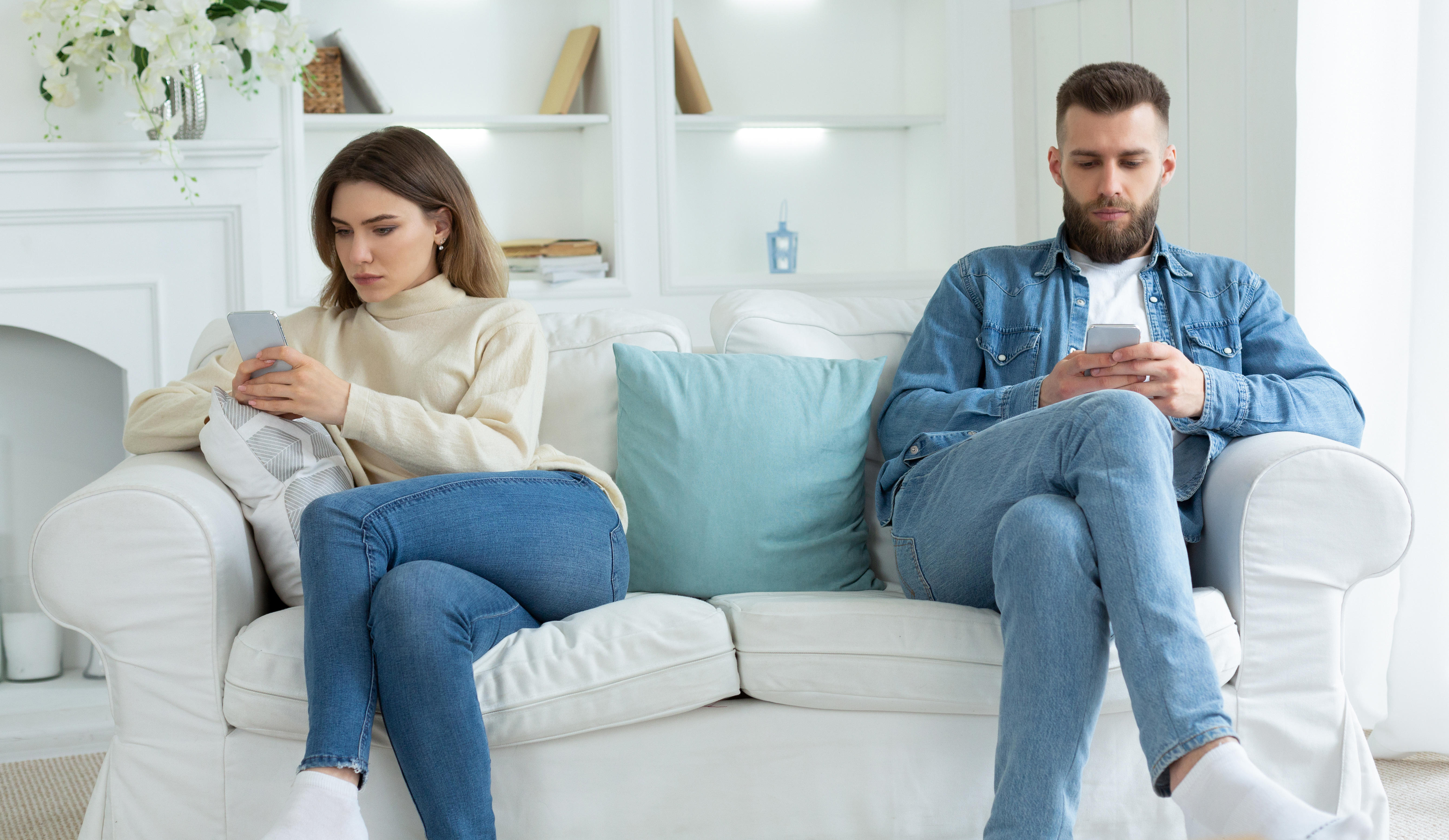Couple at opposite ends of sofa on their phones