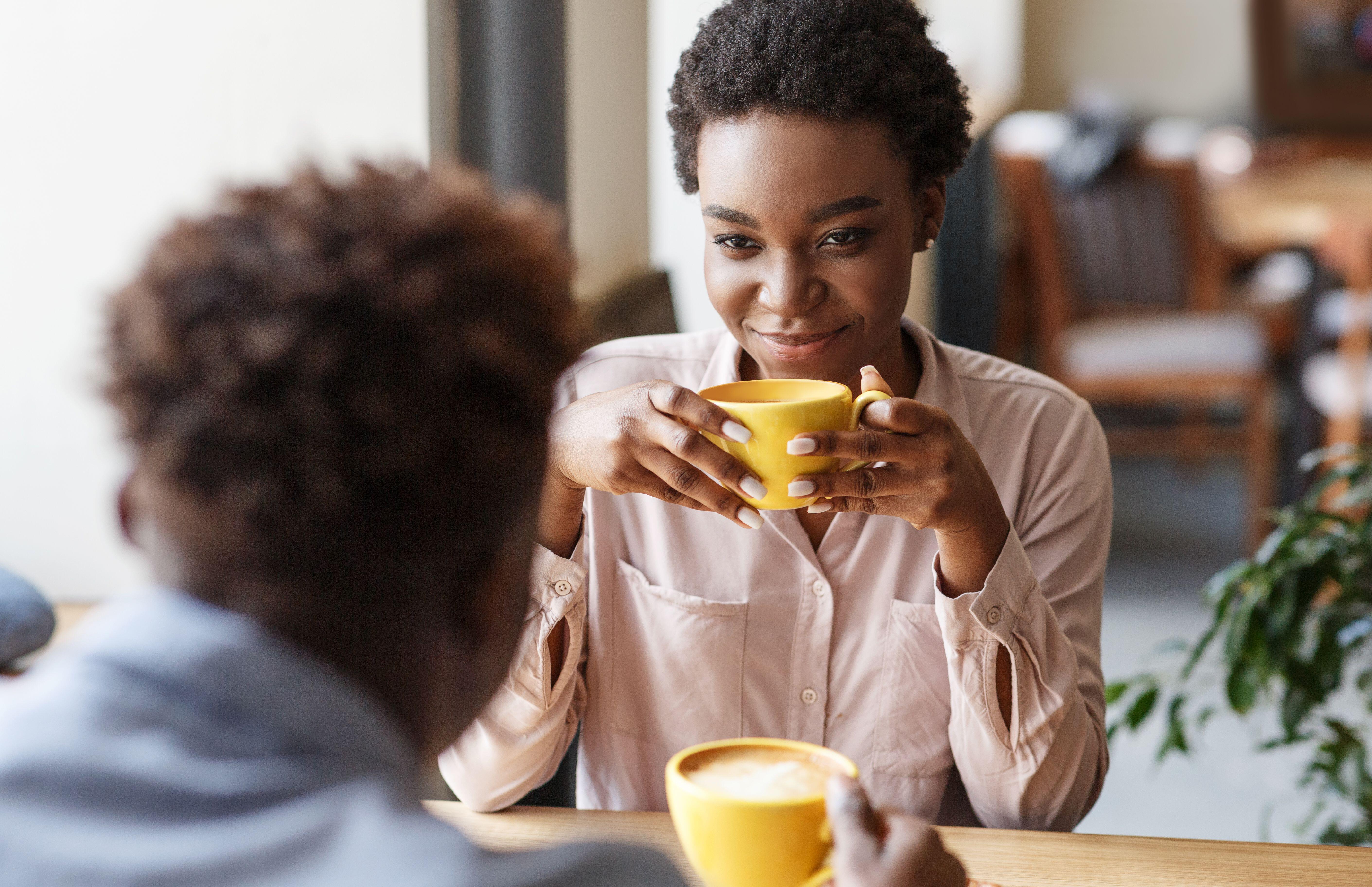 Young black couple drinking coffee together on date at cafe