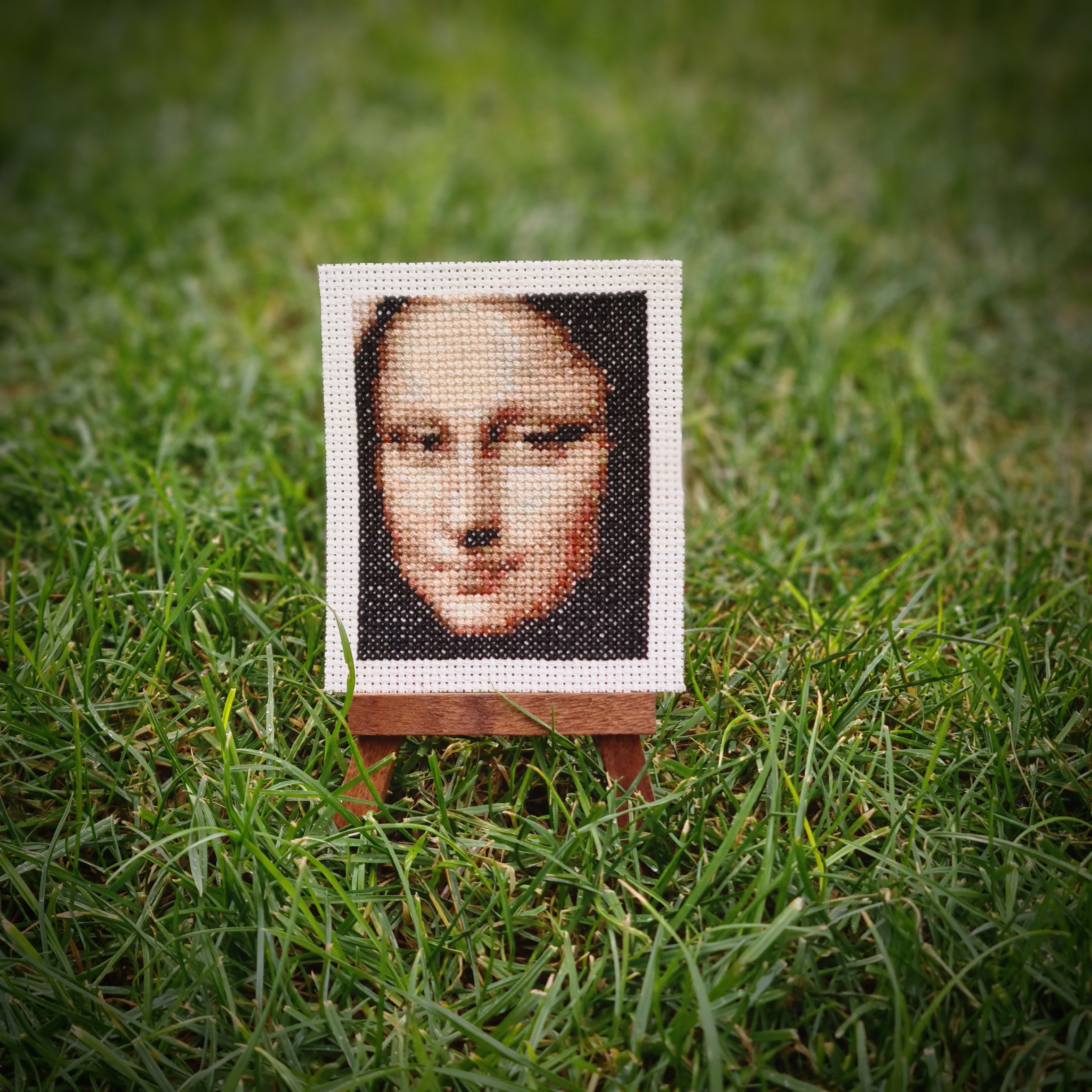 Cross-stitched Mona Lisa on a tiny easel.