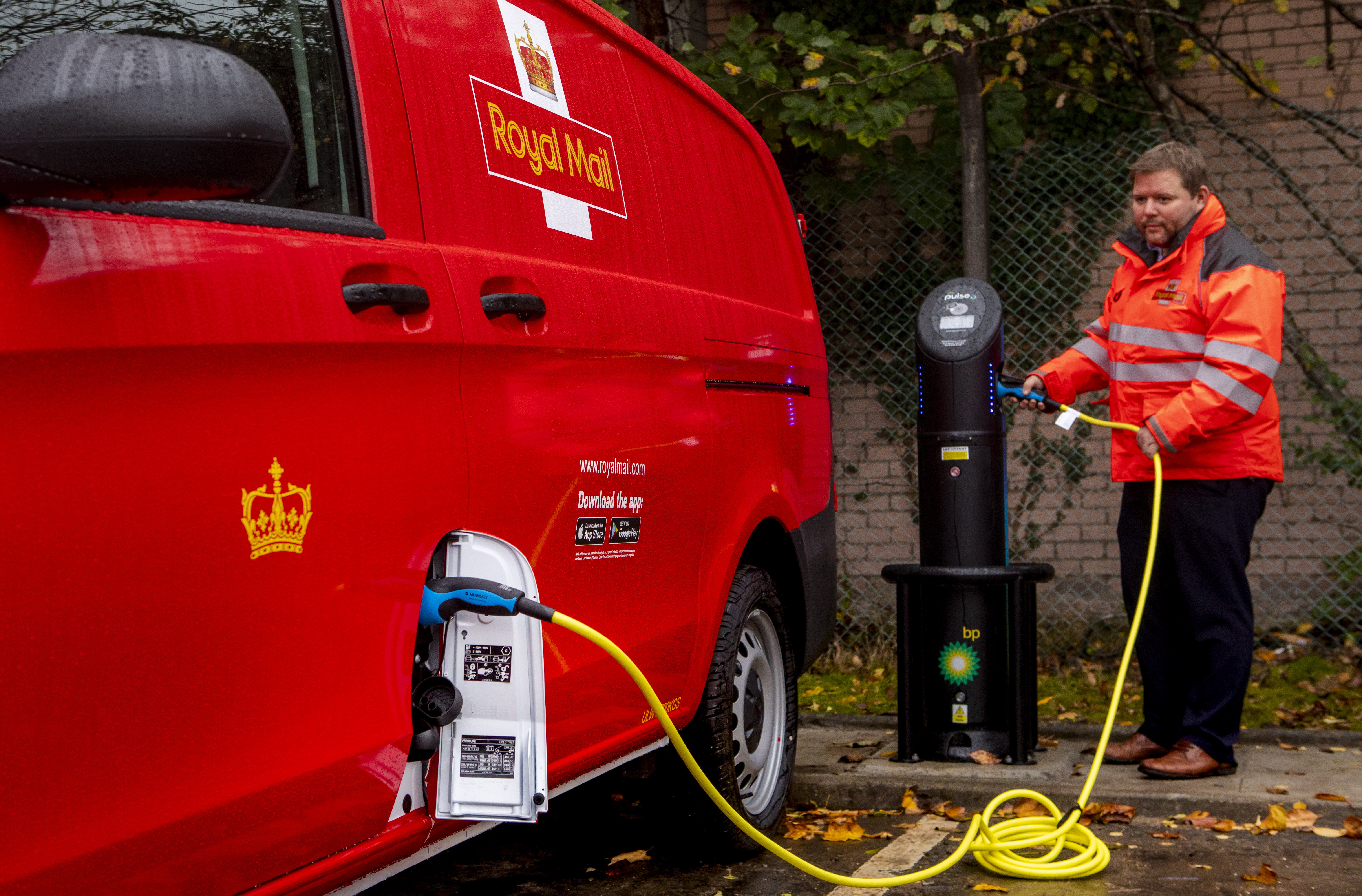 A Royal Mail worker charges an electric van