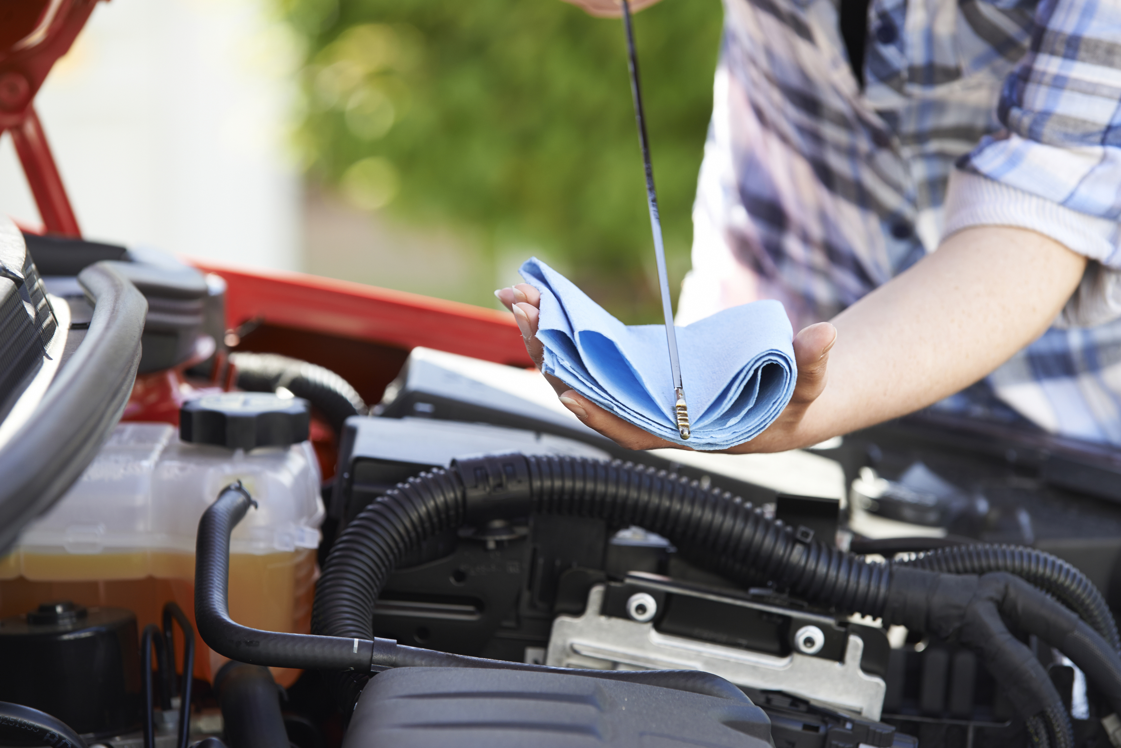 Close-Up Of Woman Checking Car Engine Oil Level On Dipstick