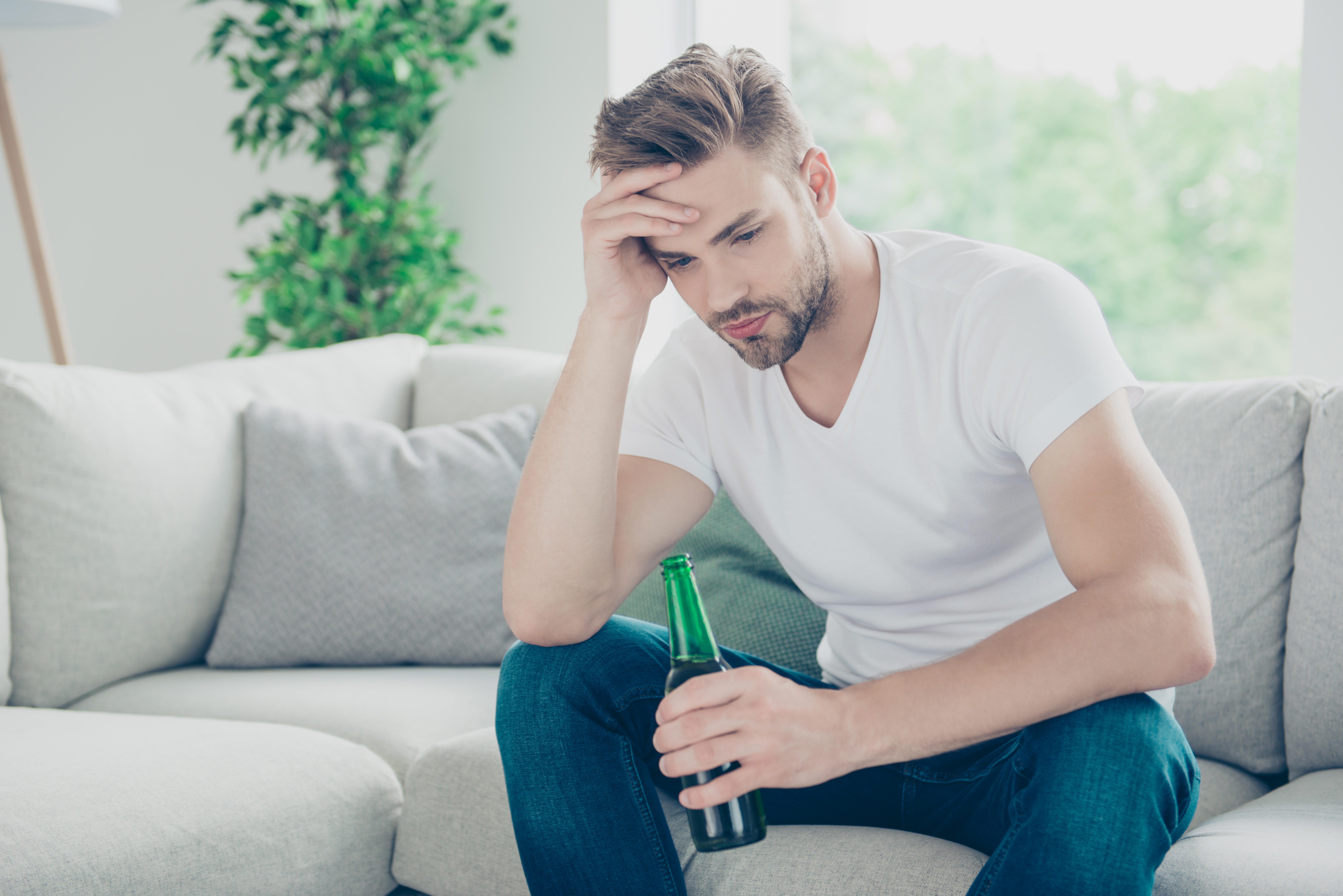 a stressed man holding a bottle of beer