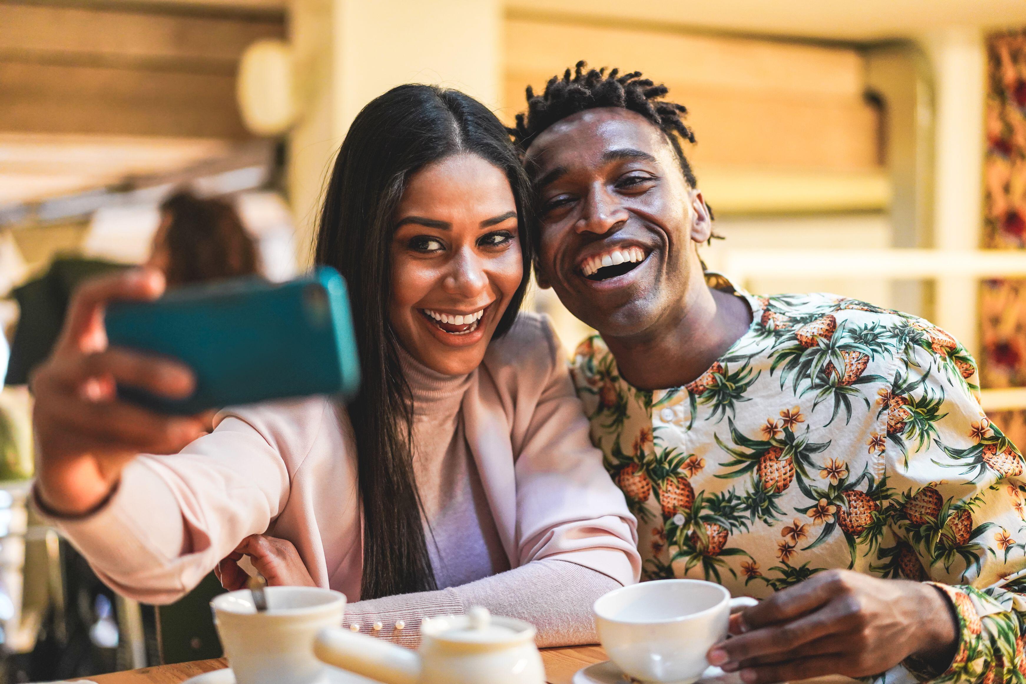 Smiling man and woman taking a selfie together in a cafe