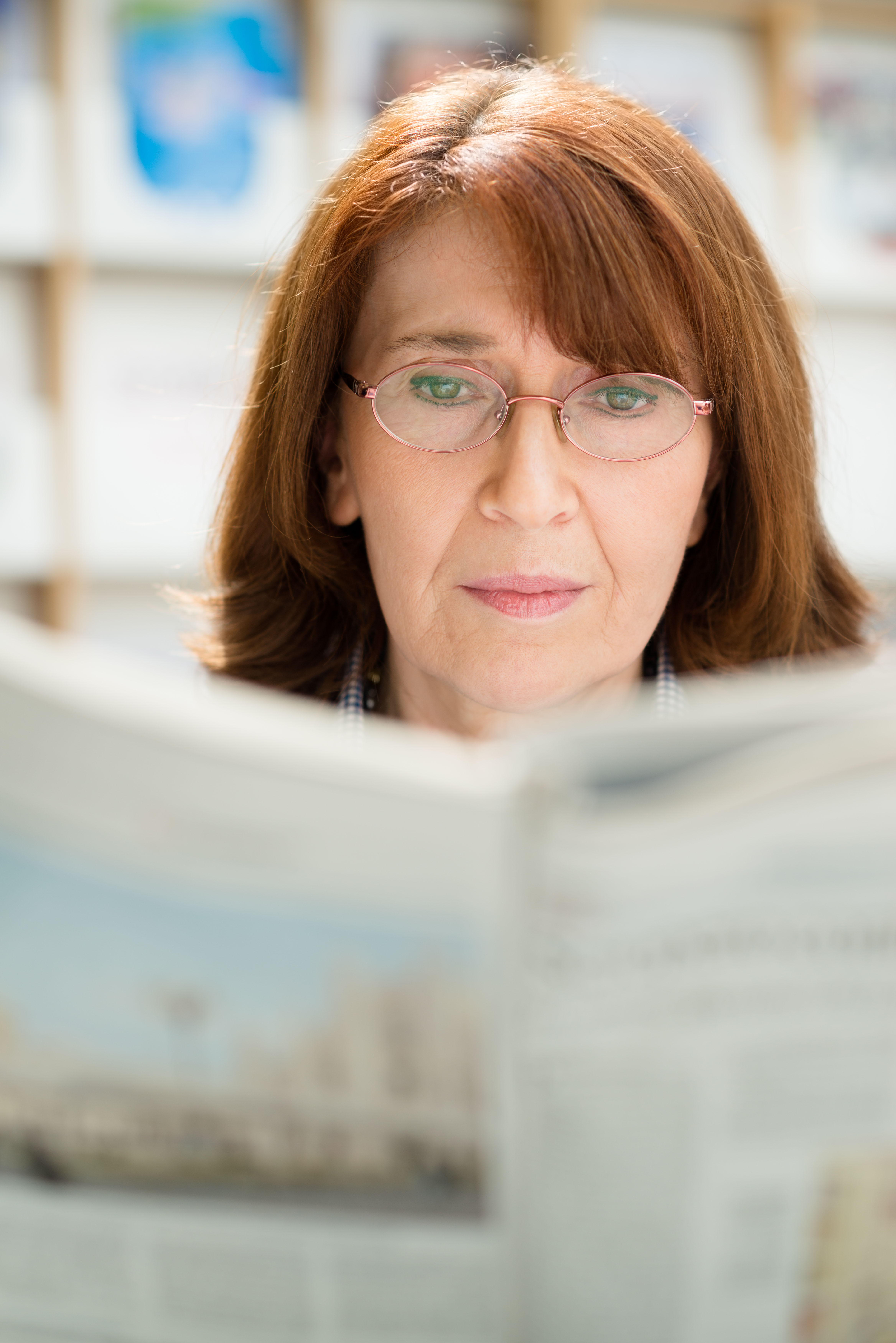 Portrait of middle aged woman with eyeglasses reading newspaper 