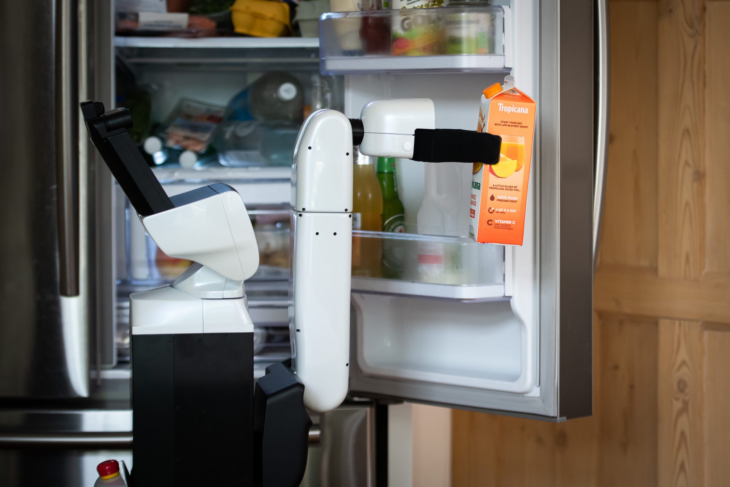 The Toyota Human Support Robot taking a orange juice carton from a fridge