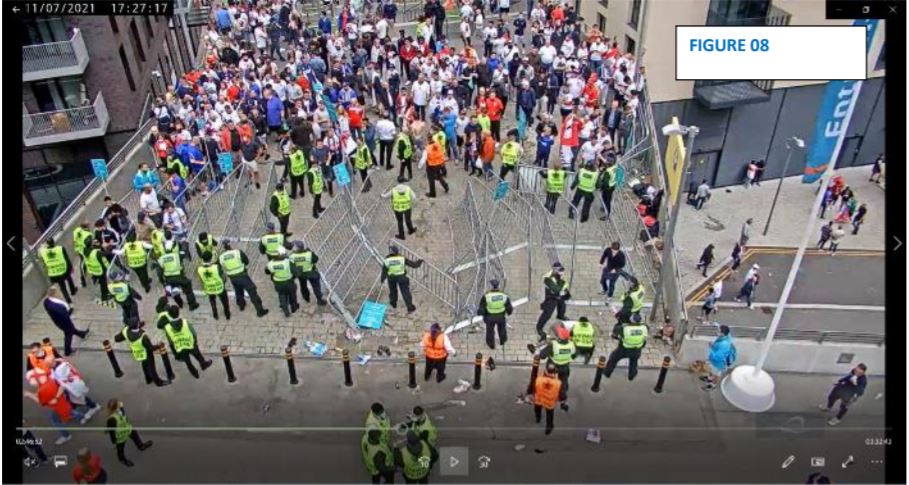 In bottom right of image, a steward stood just in front of a police officer wearing a red baseball cap bends down in front of a supporter in a white t-shirt who is believed to have suffered a seizure in the earlier surge 