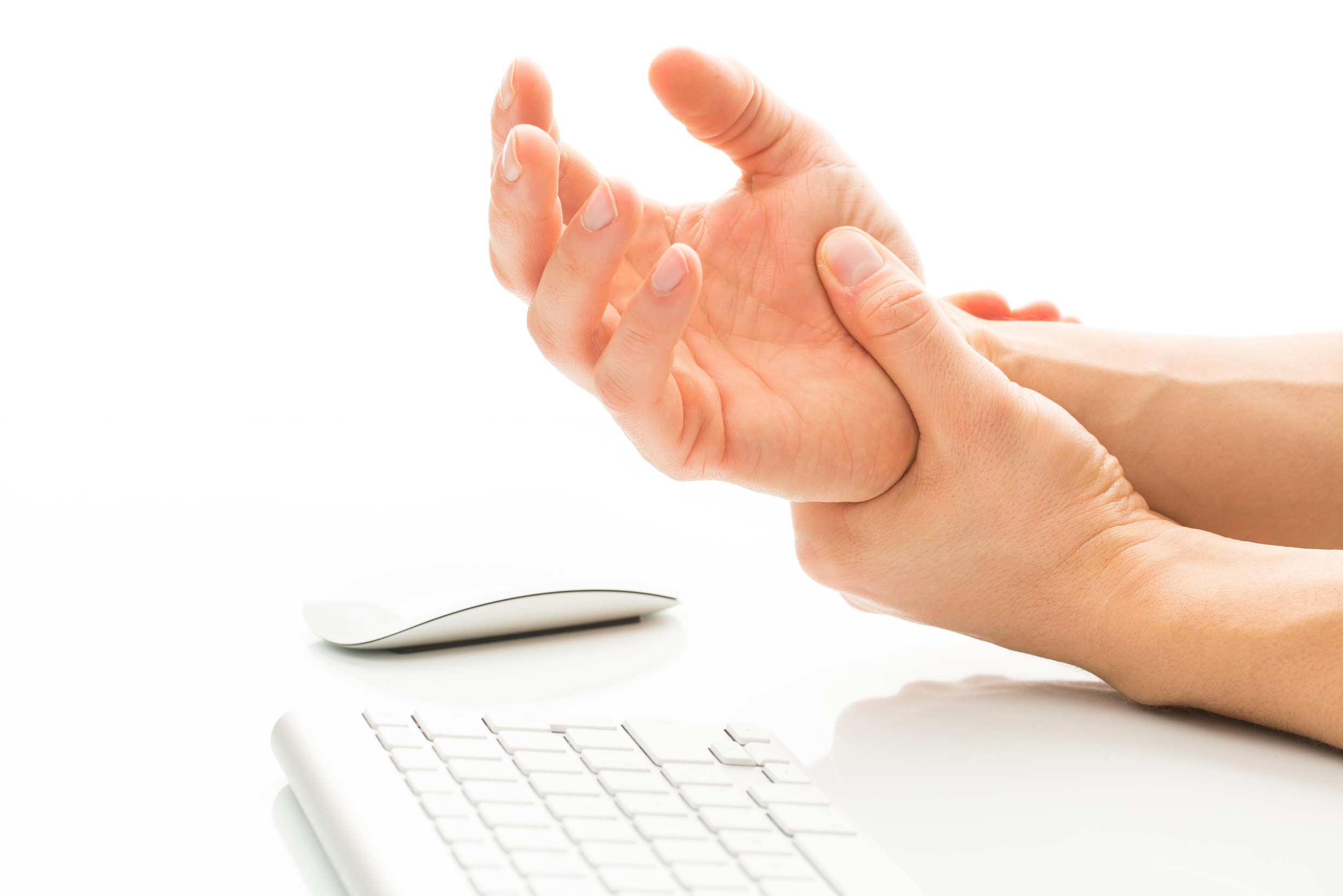 Young man holding his wrist in pain due to prolonged use of keyboard and mouse