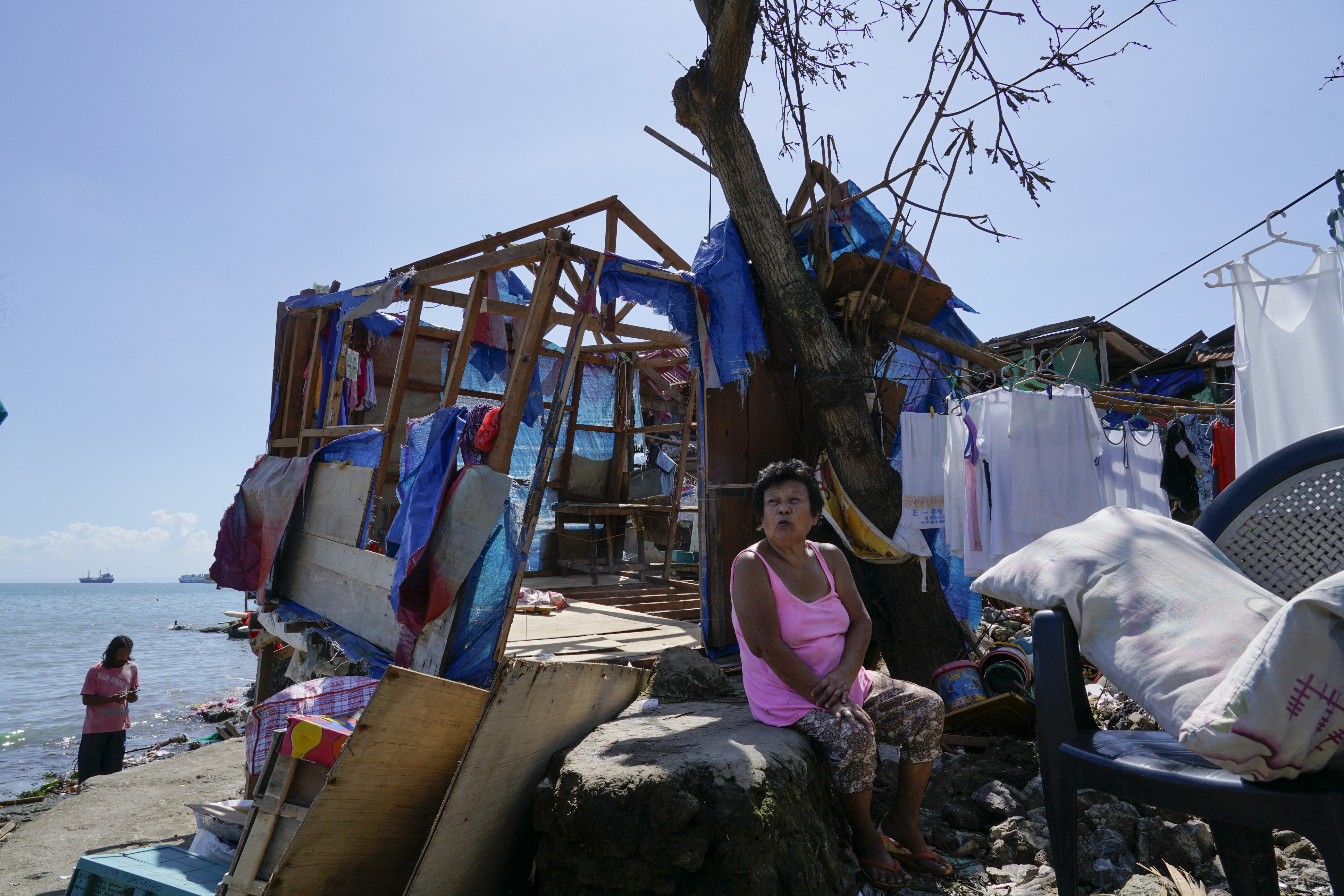 A woman sits beside damaged homes