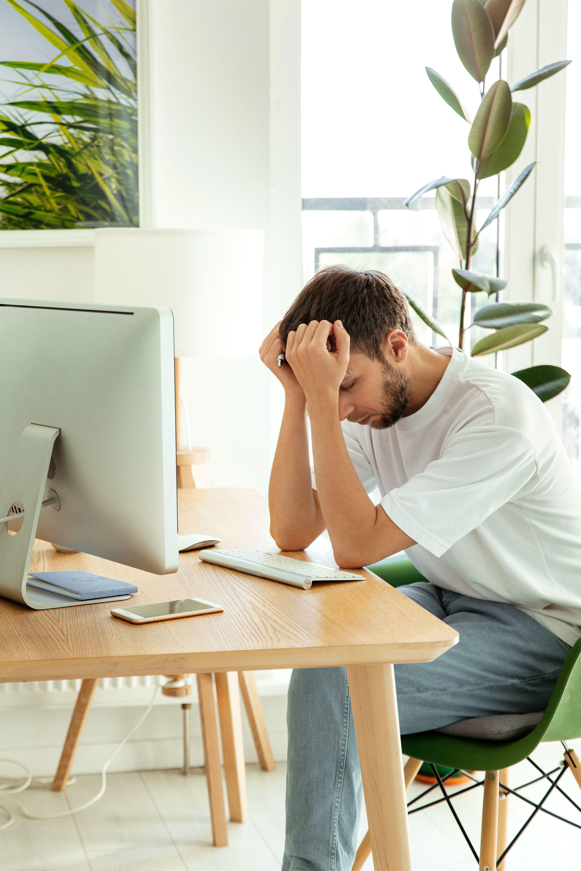 man frustrated with problems at work sitting at computer