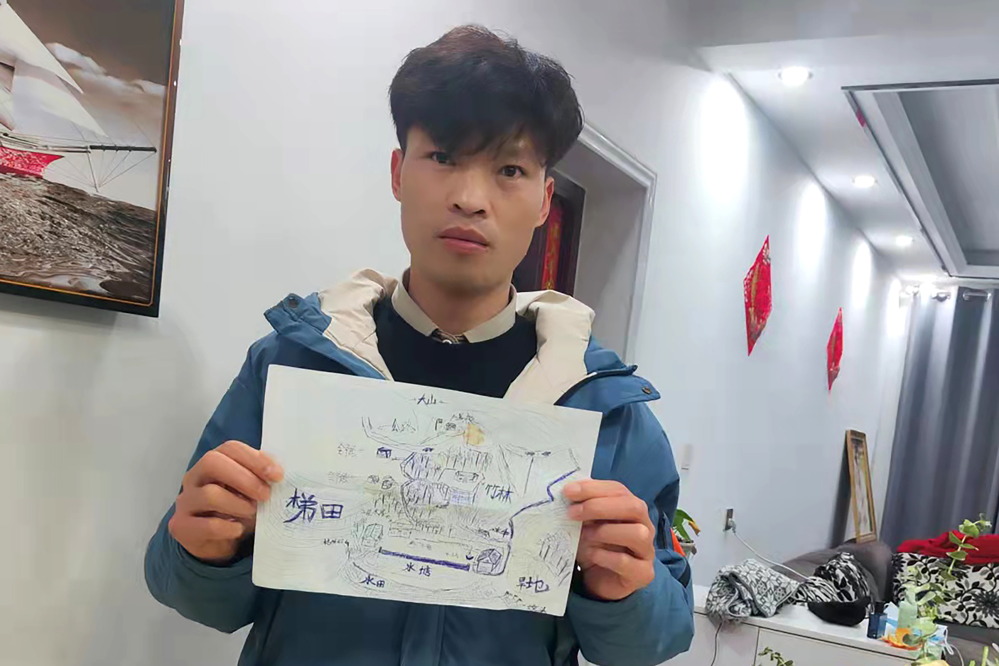 Li Jingwei holds a map he drew from memory of his childhood village as he poses for a photo in Lankao in central China's Henan Province 