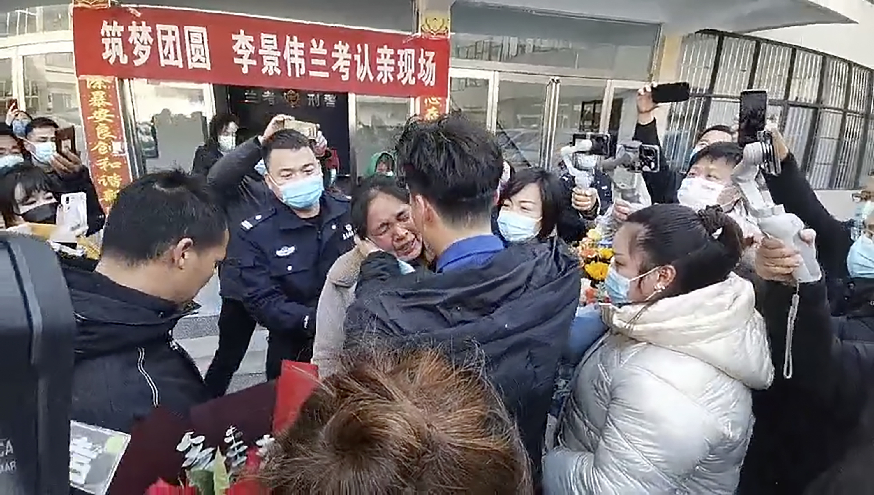 In this image taken from video, Li Jingwei, with back to camera, is reunited with his mother in Lankao in central China's Henan Province 
