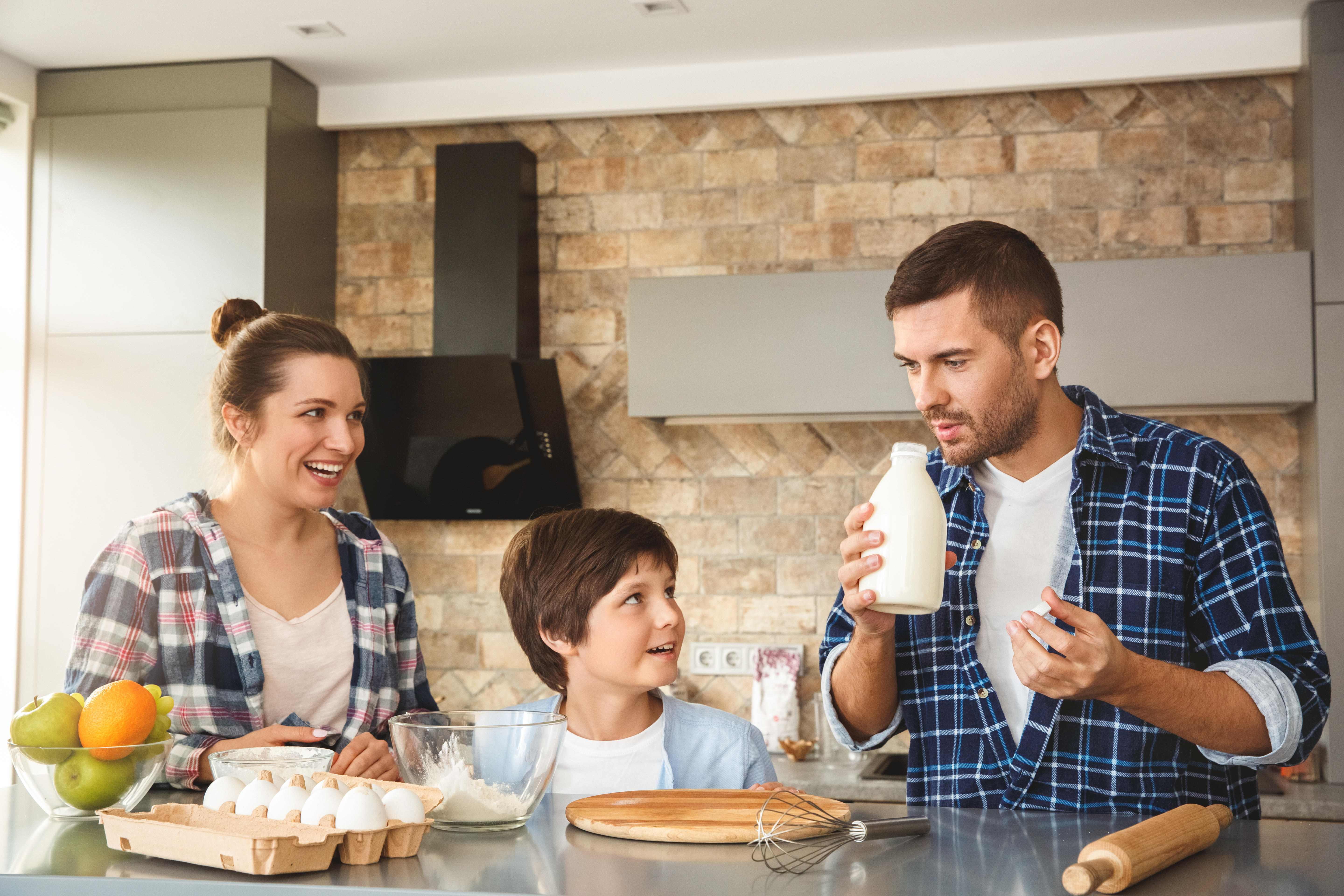 Man sniffing milk while cooking with family