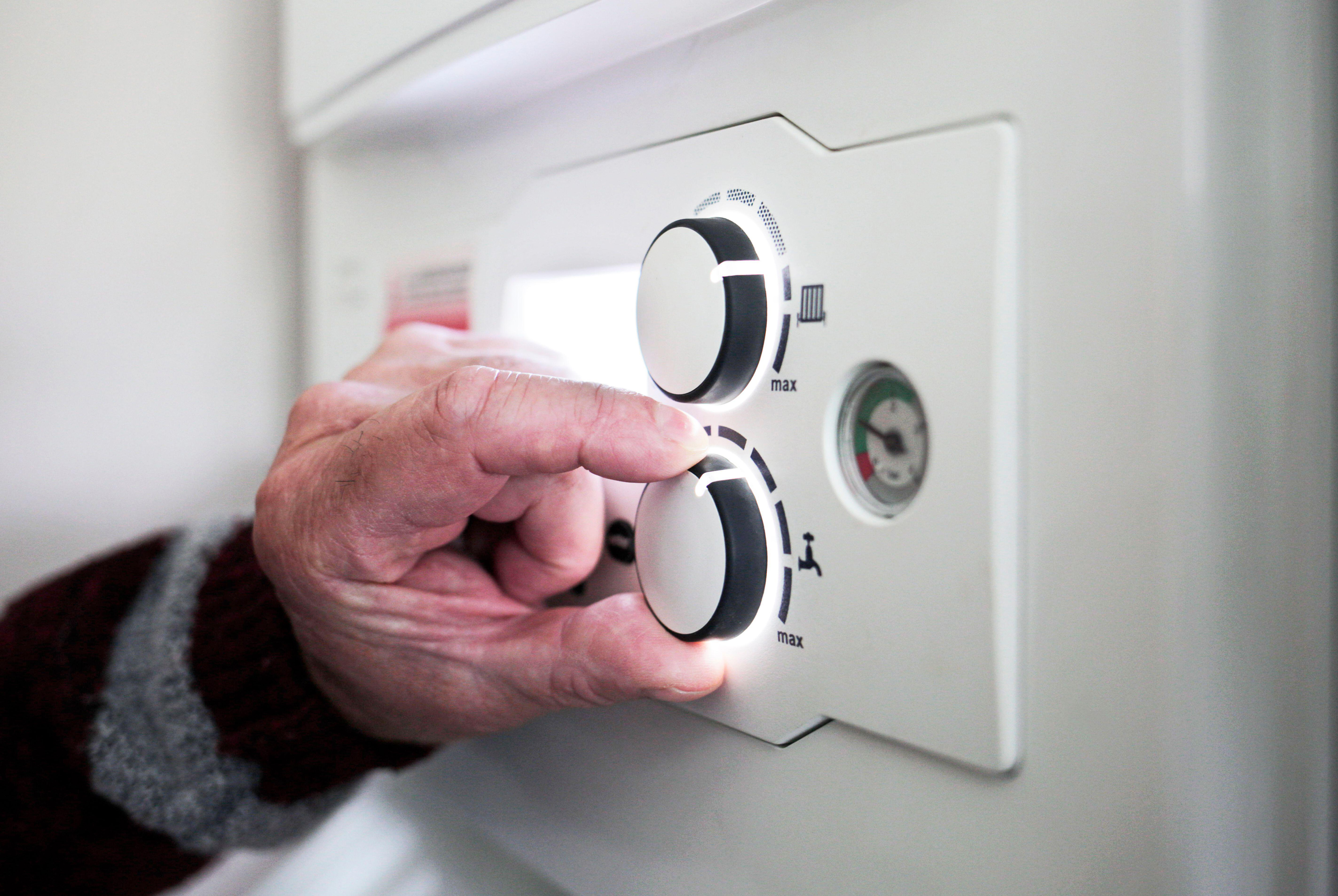 A pensioner adjusting the temperature control on his combi boiler.