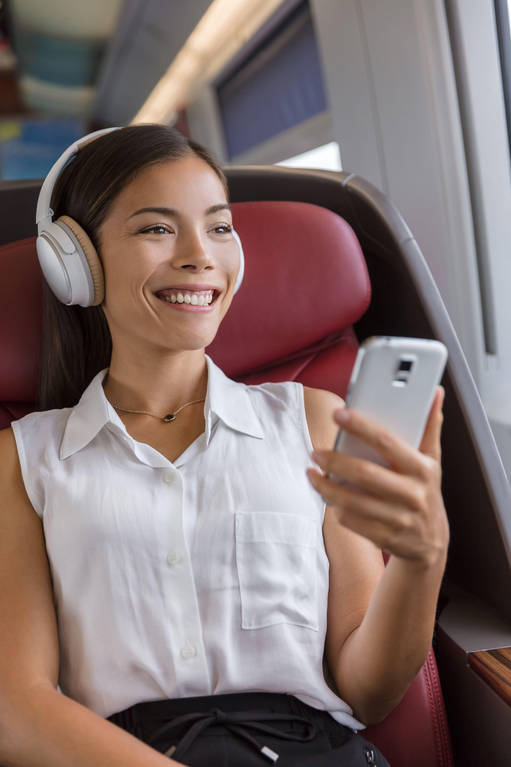 woman using phone app and wireless headphones to listen to music