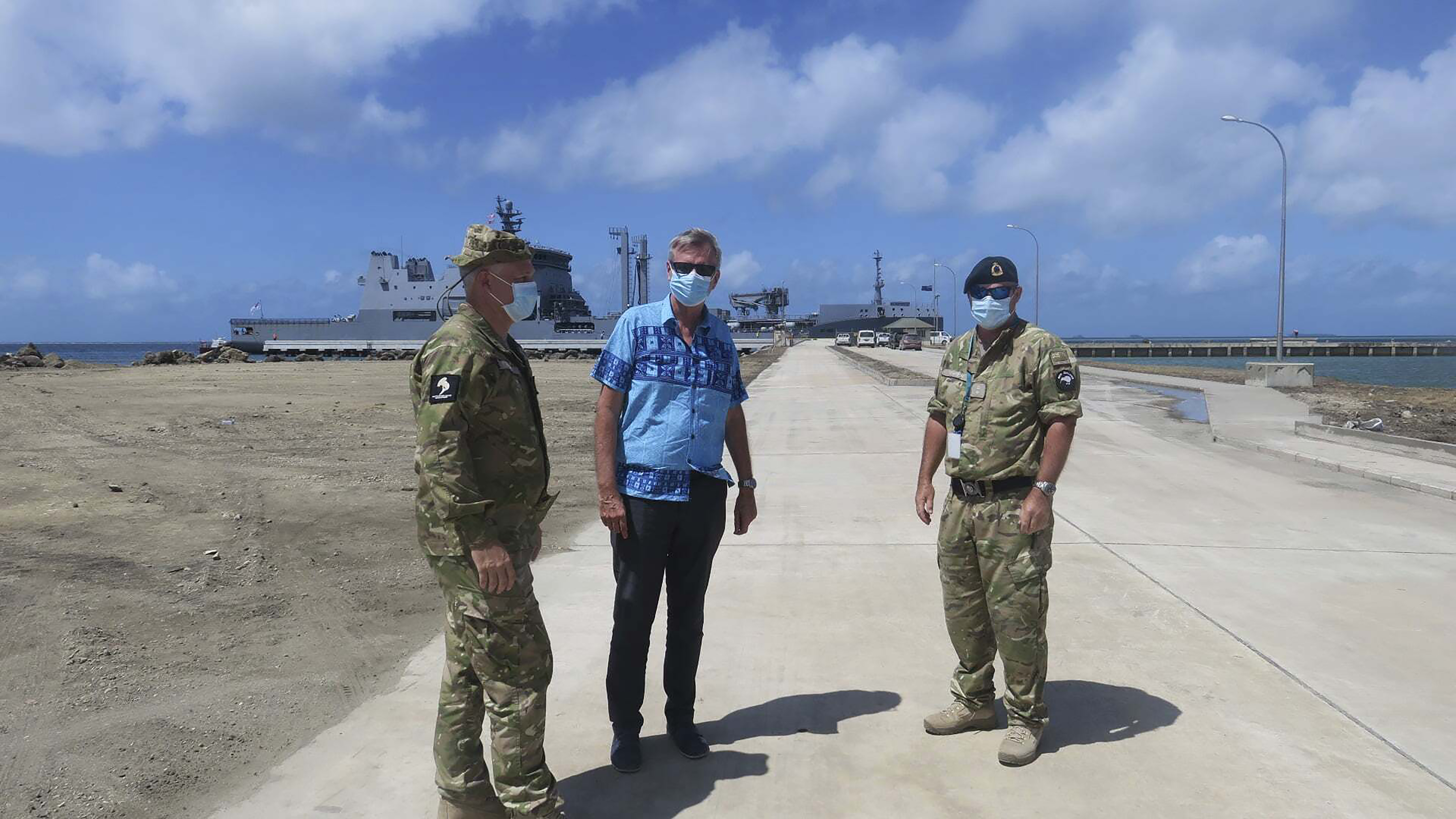 Peter Lund stands with military personnel at a wharf in Tonga 