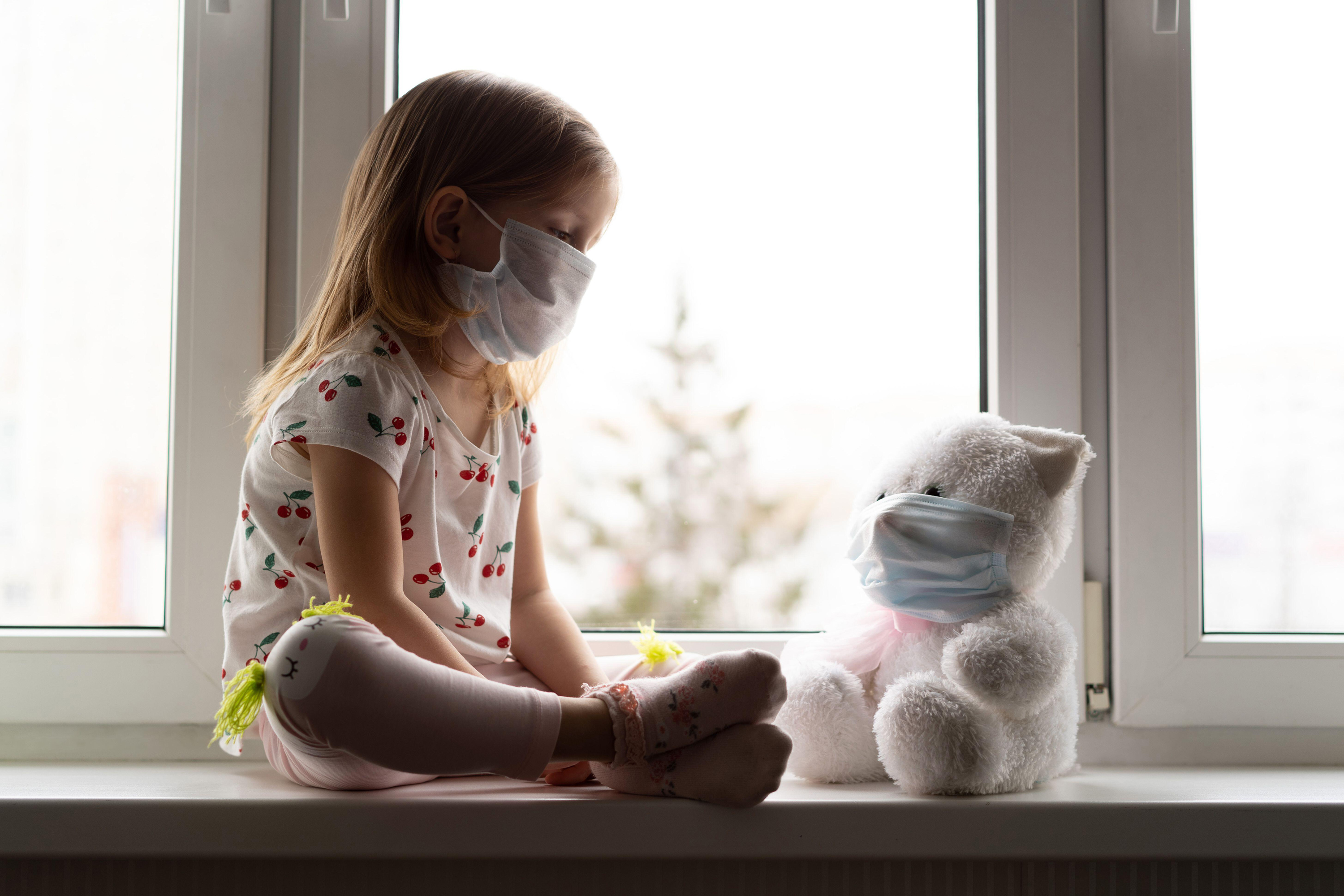 Child and teddy wearing face masks