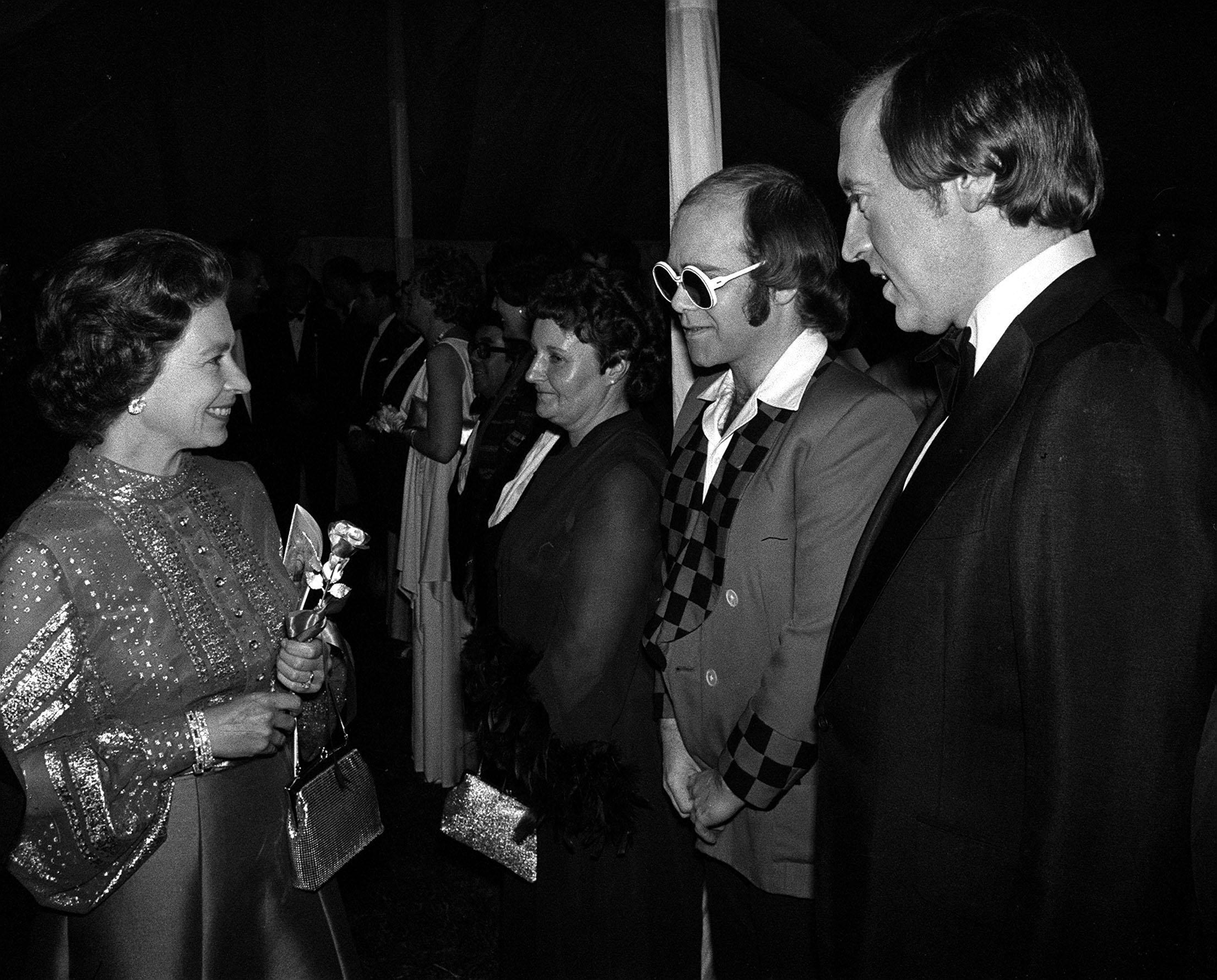 Bespectacled pop star Elton John and television personality David Frost being presented to the Queen at Windsor