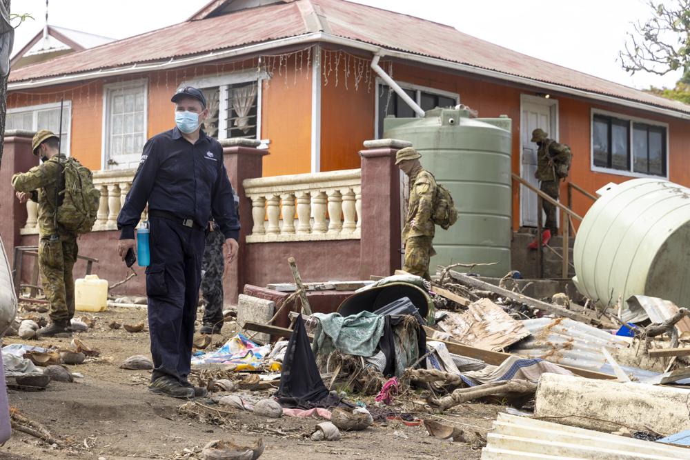 Australian Defence Force and Department of Foreign Affairs & Trade crisis personnel stand amid the rubble outside a house in Tonga