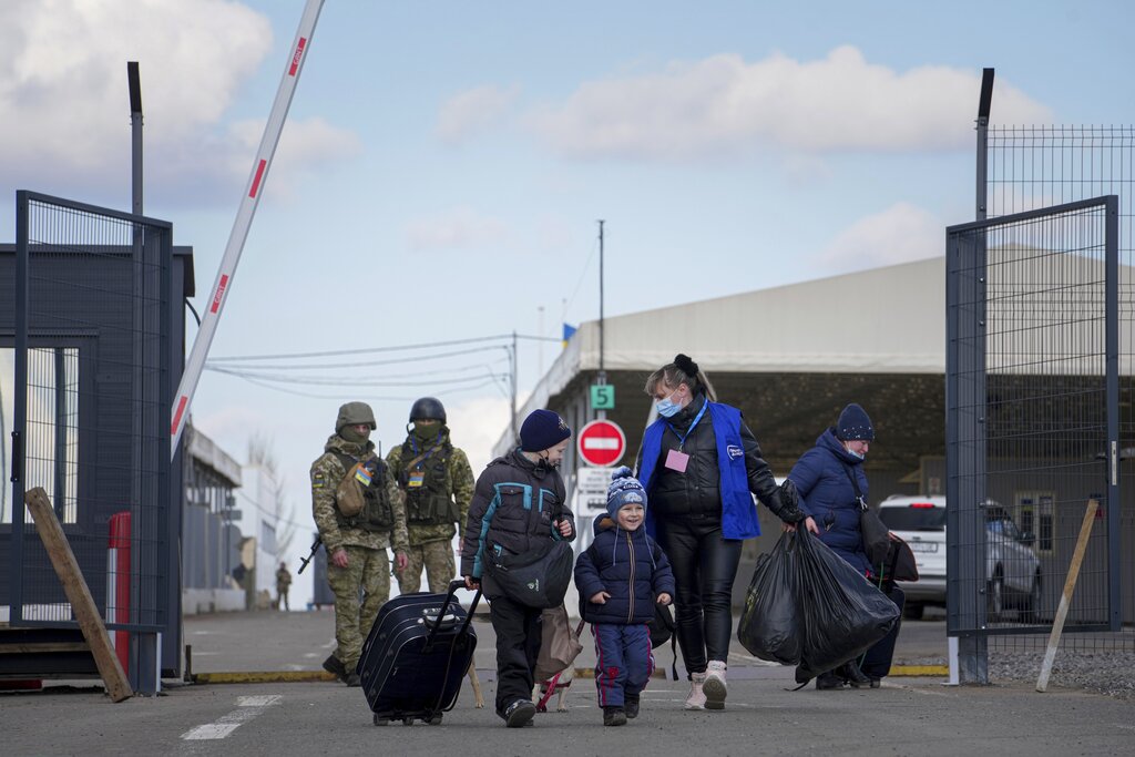 A woman with her children crosses a checkpoint from territory controlled by Russia-backed separatists to the territory controlled by Ukrainian forces in Novotroitske, eastern Ukraine