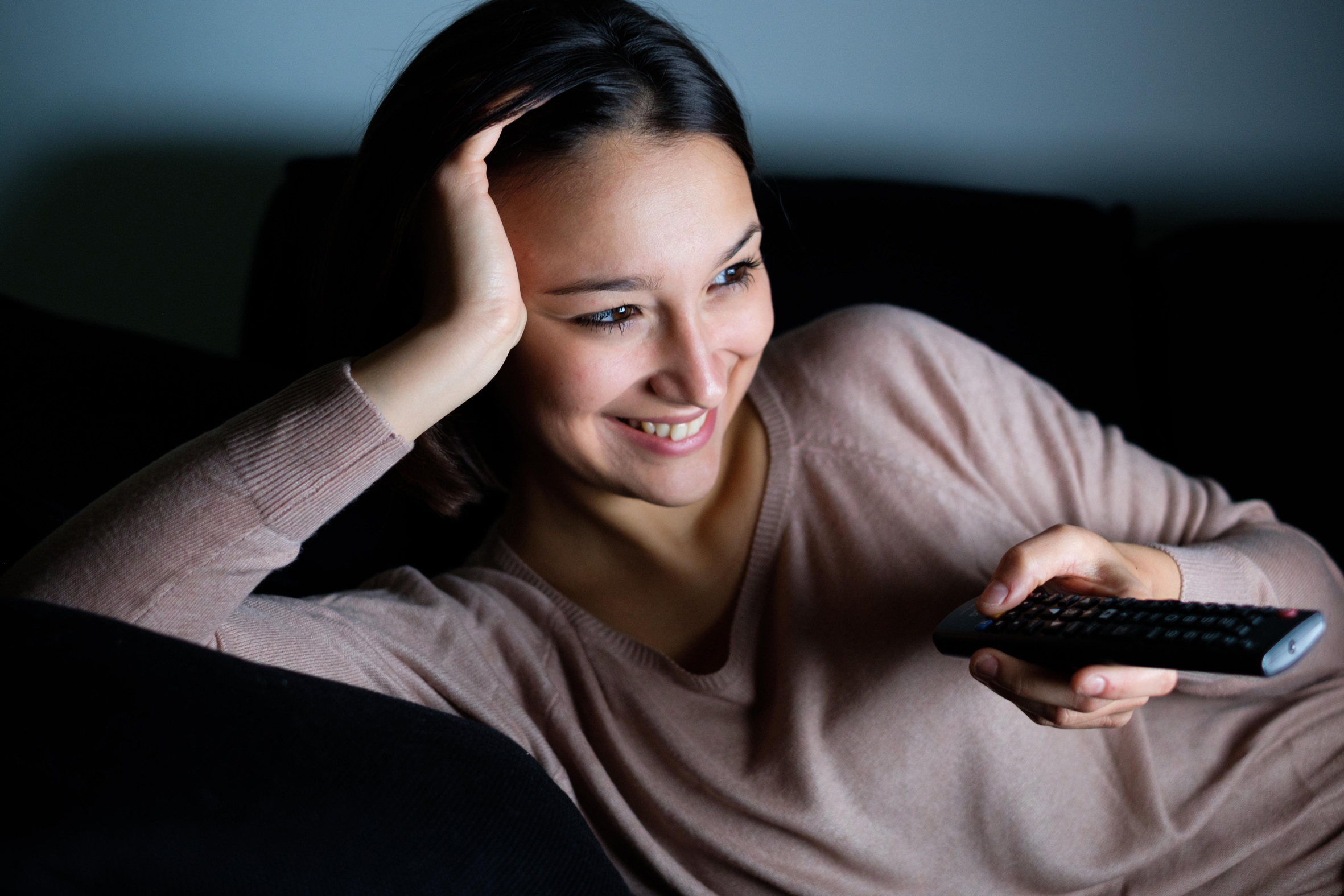 Woman with television remote watching a movie