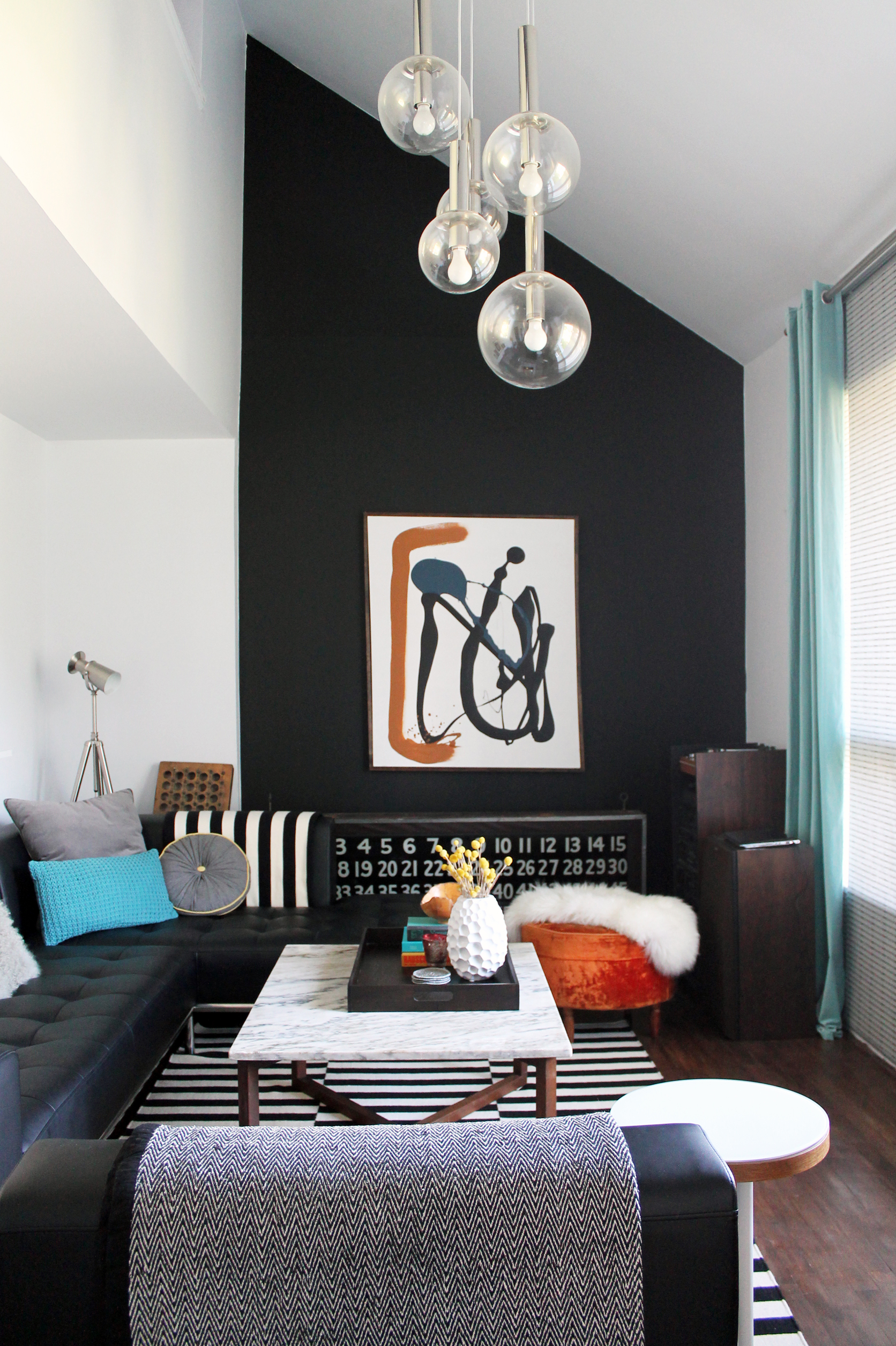 Small living room with a dark wall as a focal point, art work and statement lighting