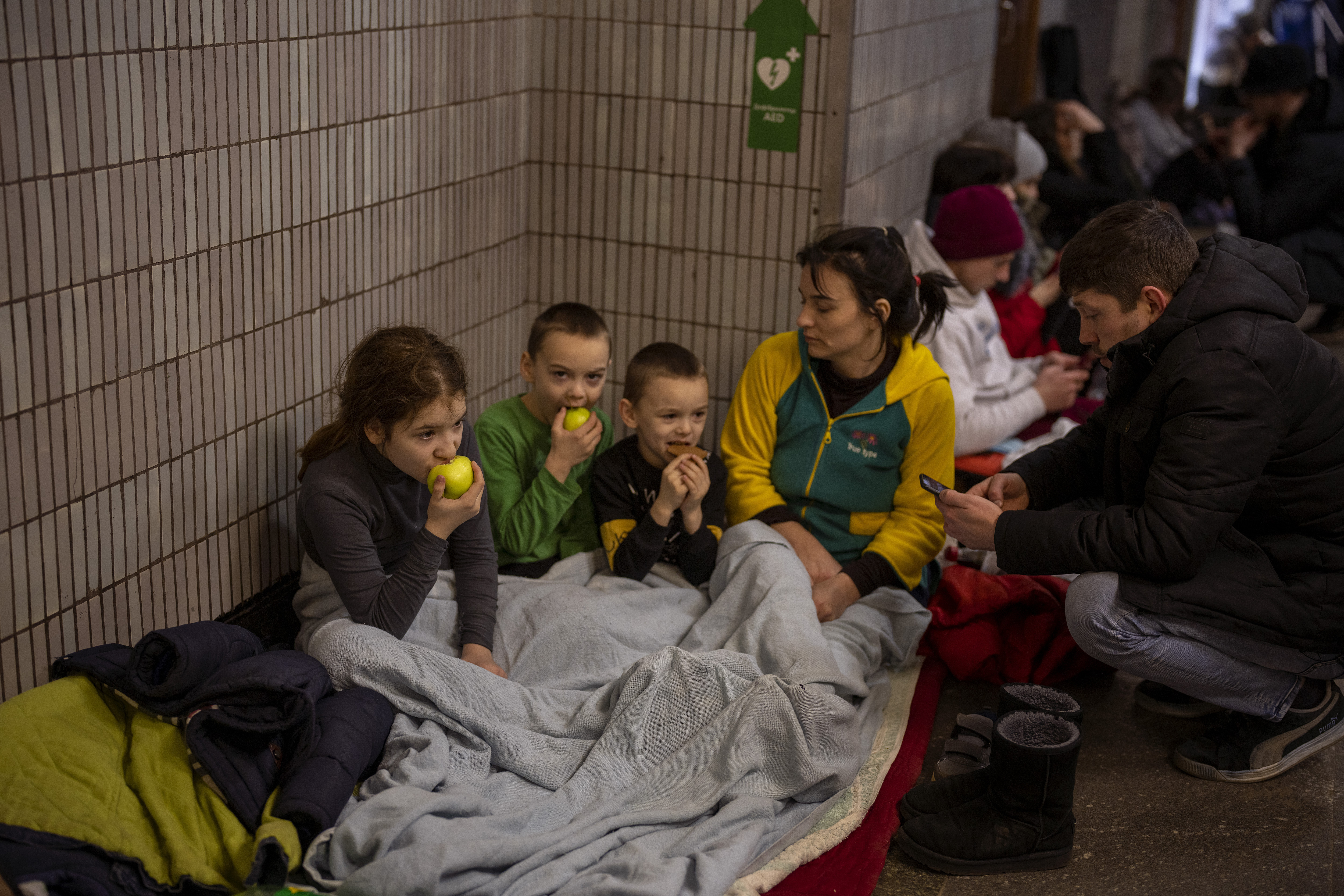 A family sit in the Kyiv subway, using it as a bomb shelter 