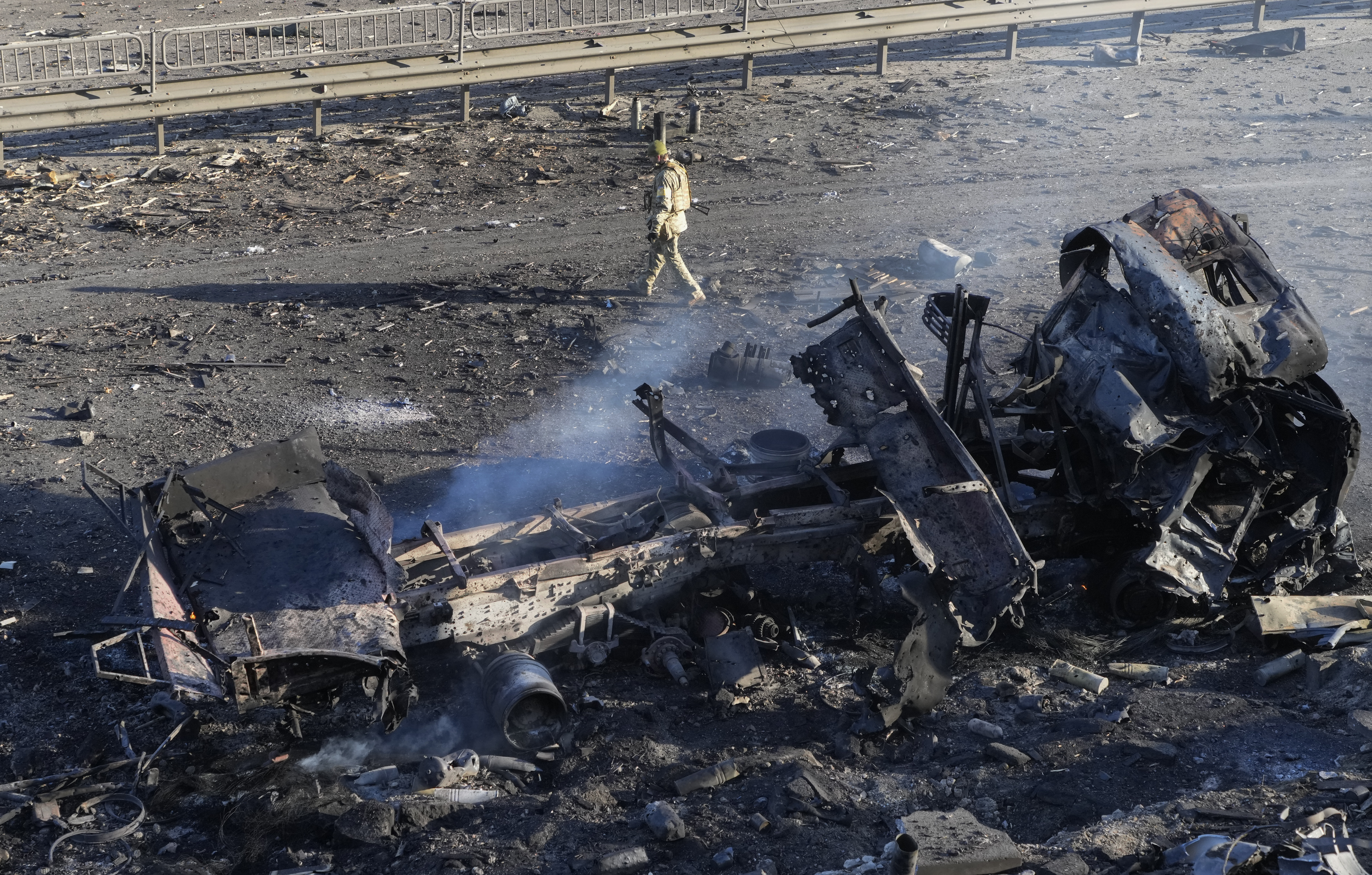 A Ukrainian soldier walks past debris of a burning military truck, on a street in Kyiv