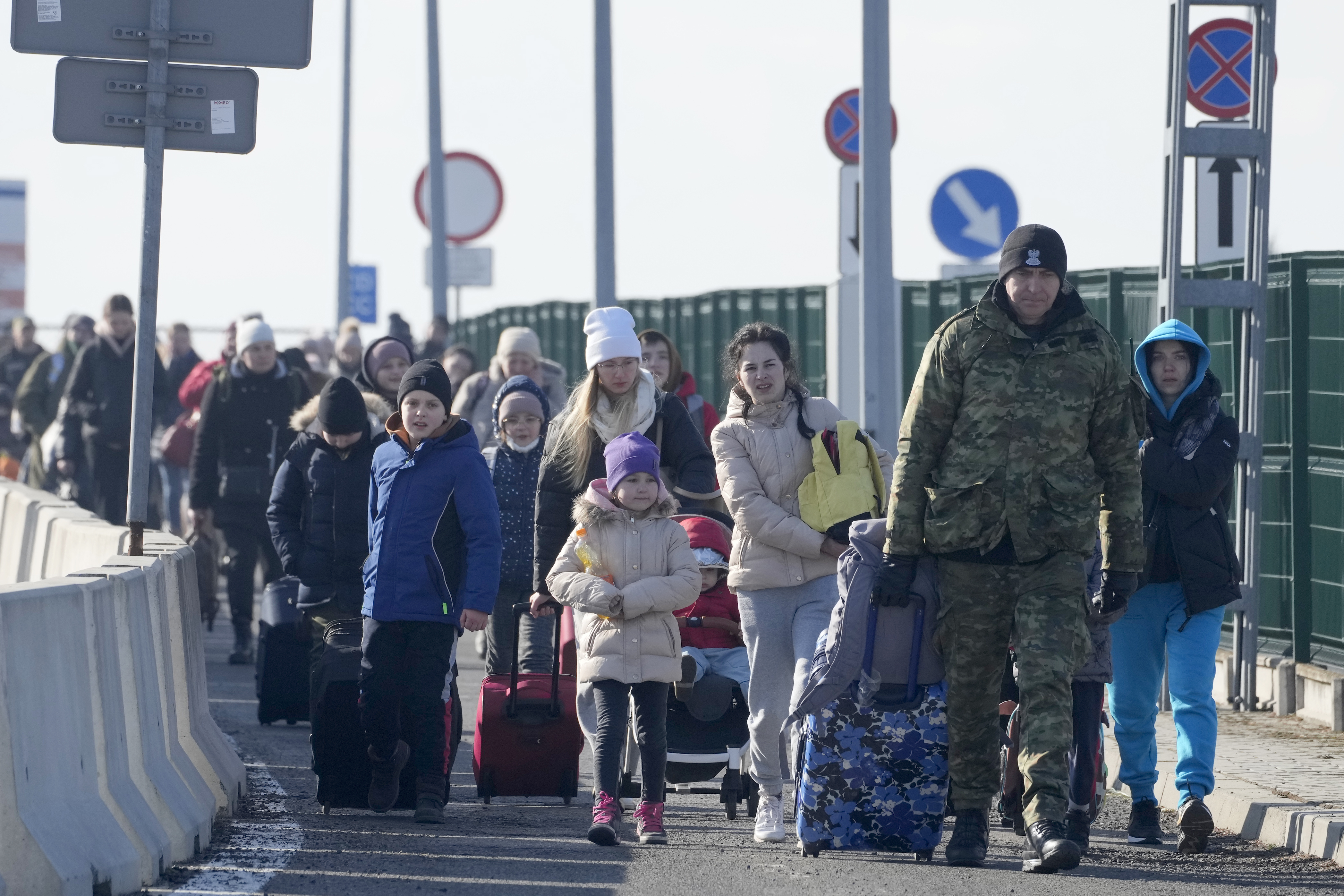 A Polish border guard assists refugees from Ukraine as they arrive to Poland at the Korczowa border crossing, Poland, Saturday, Feb. 26, 2022.