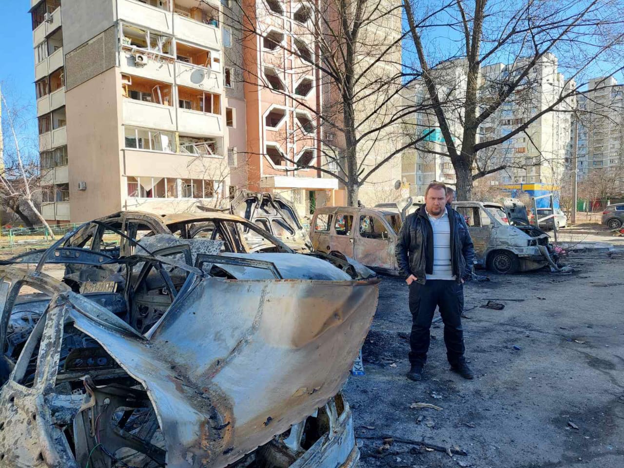 Vitaliy Rulyov stood next to burnt out cars in Kyiv