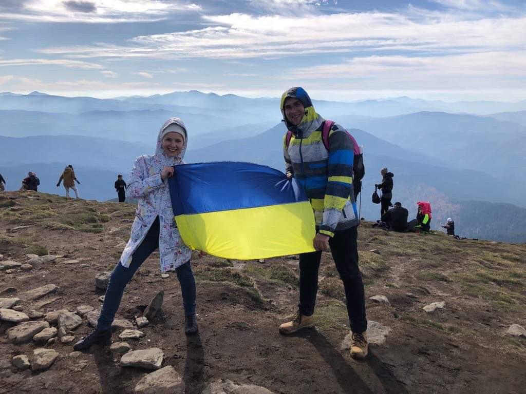 Roman Tymchyshyn (left) with his wife Ulyana Vovk holding a Ukrainian flag.