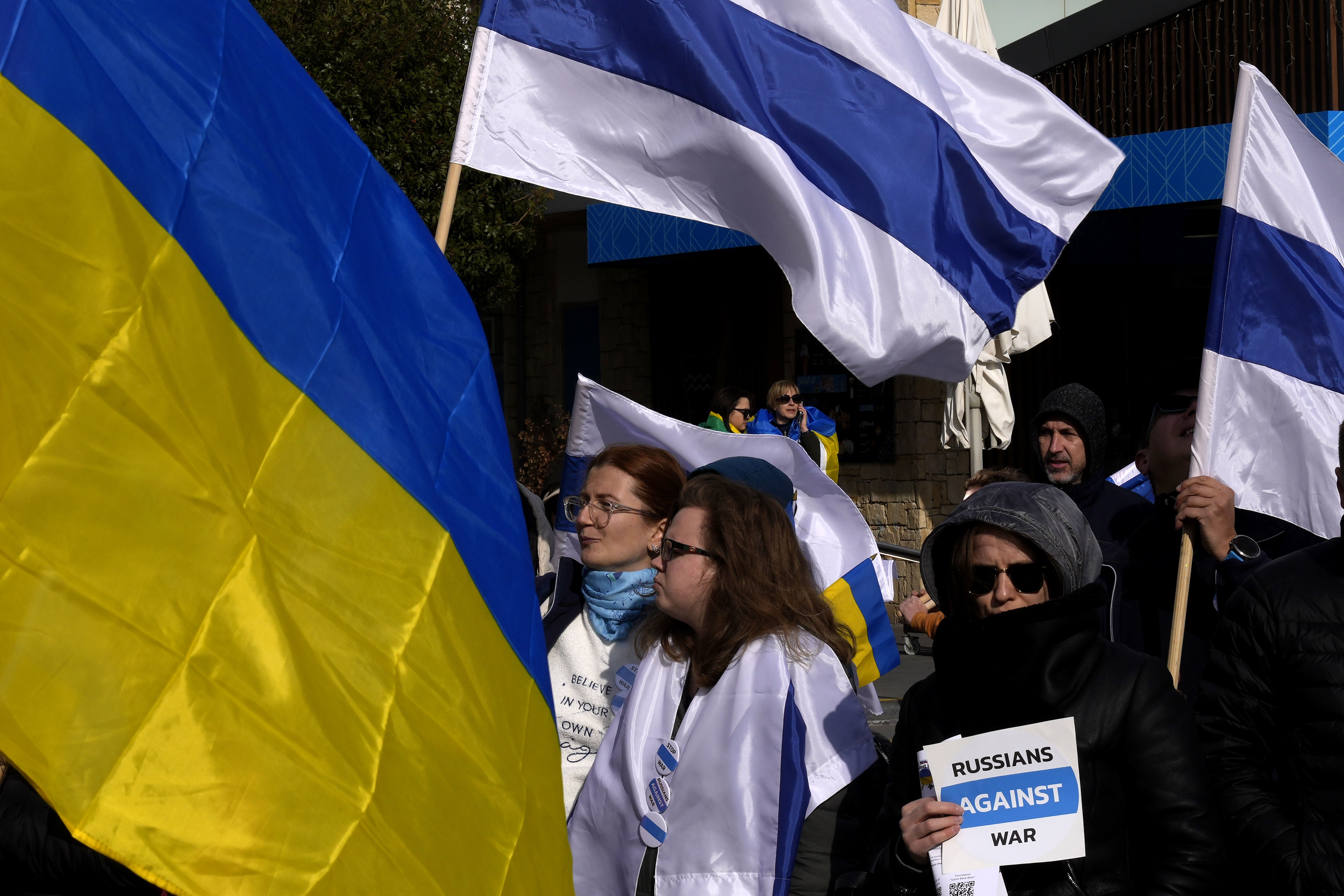 Russian protesters living in Cyprus wave Ukrainian and Russian national flags without the red stripe during a protest against Russia's invasion of Ukraine 