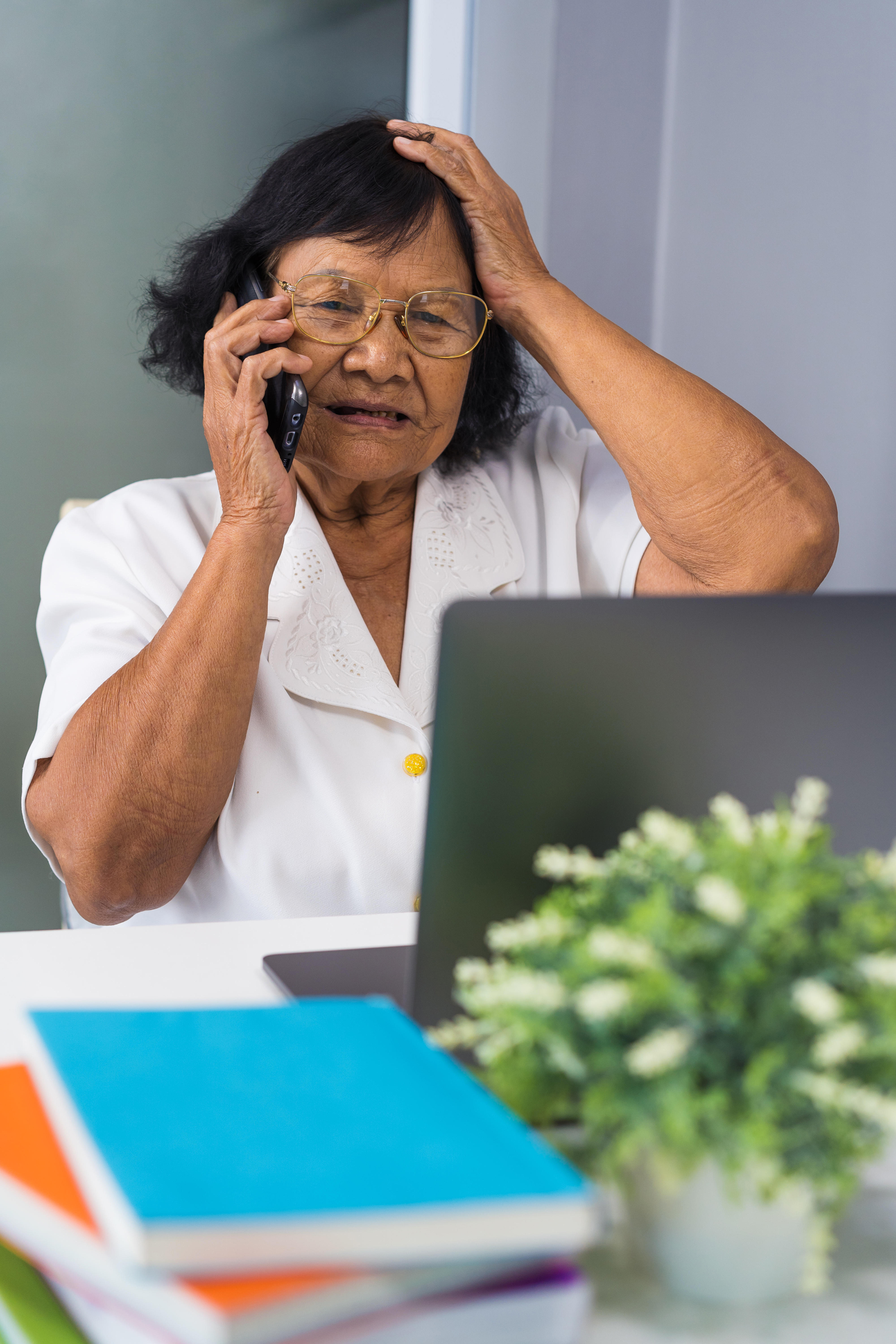 Stressed woman on phone and laptop