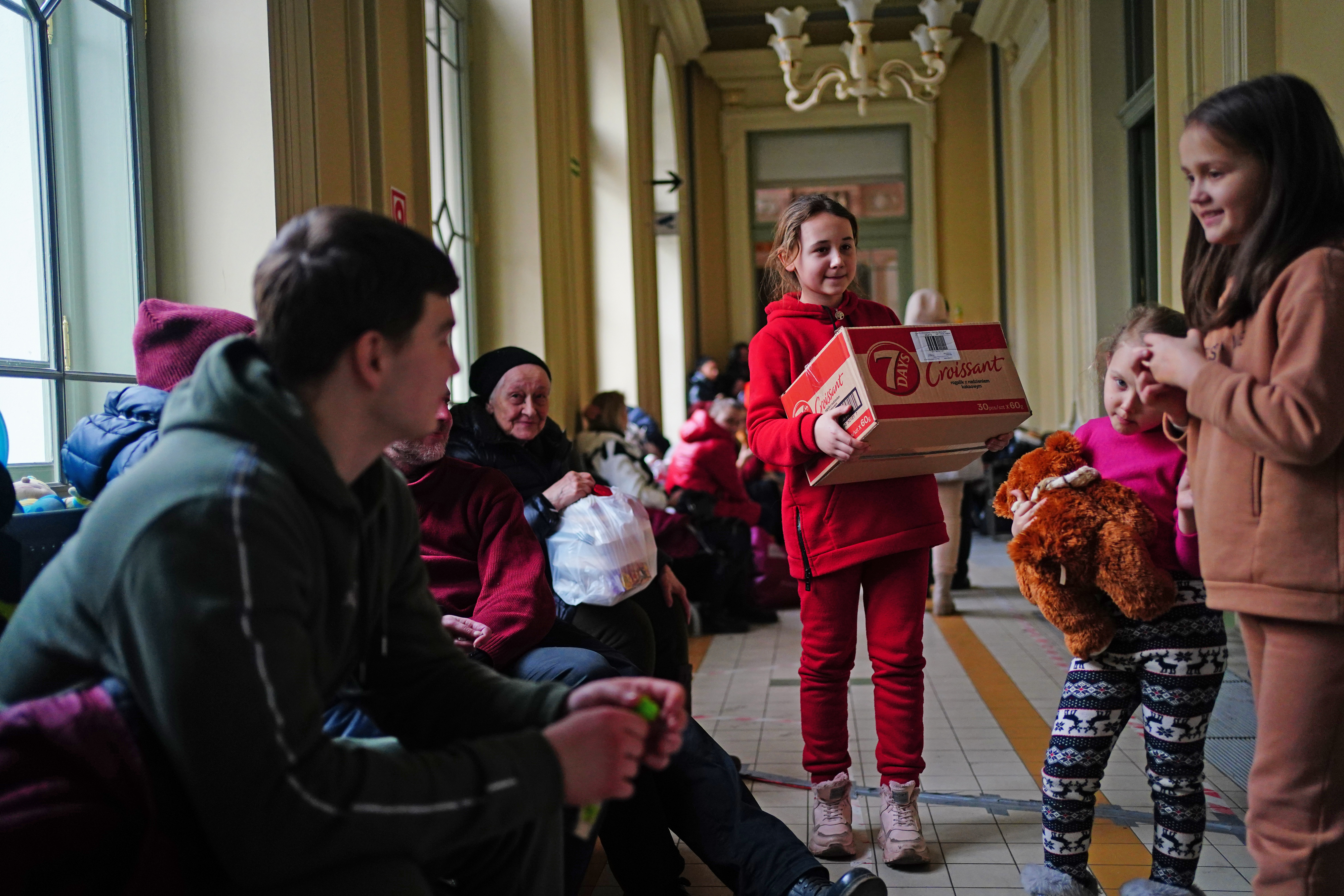 A girl from Ukraine hands food to refugees at Przemysl train station in Poland. 