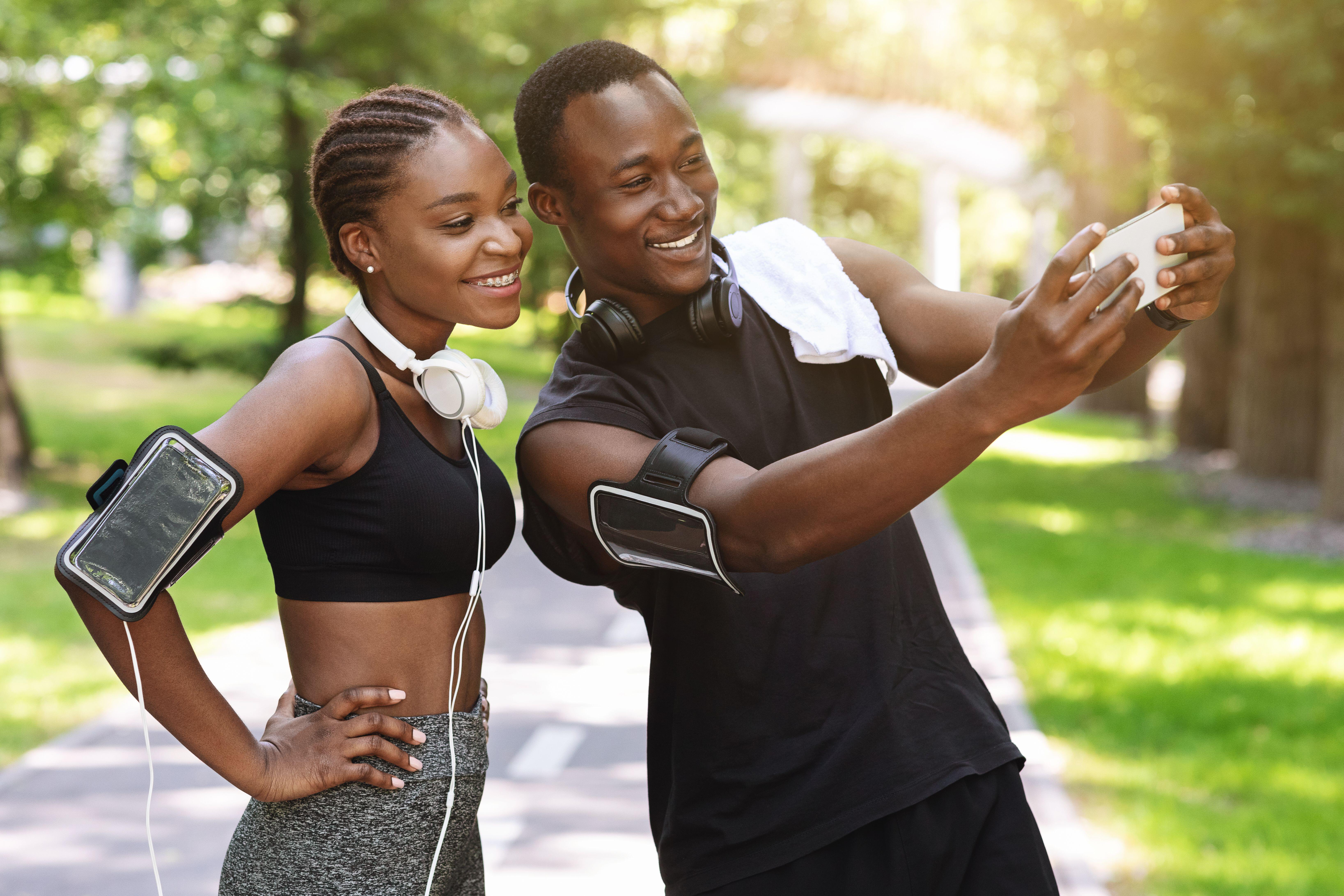 A man and woman out in running gear, taking a selfie in the sun