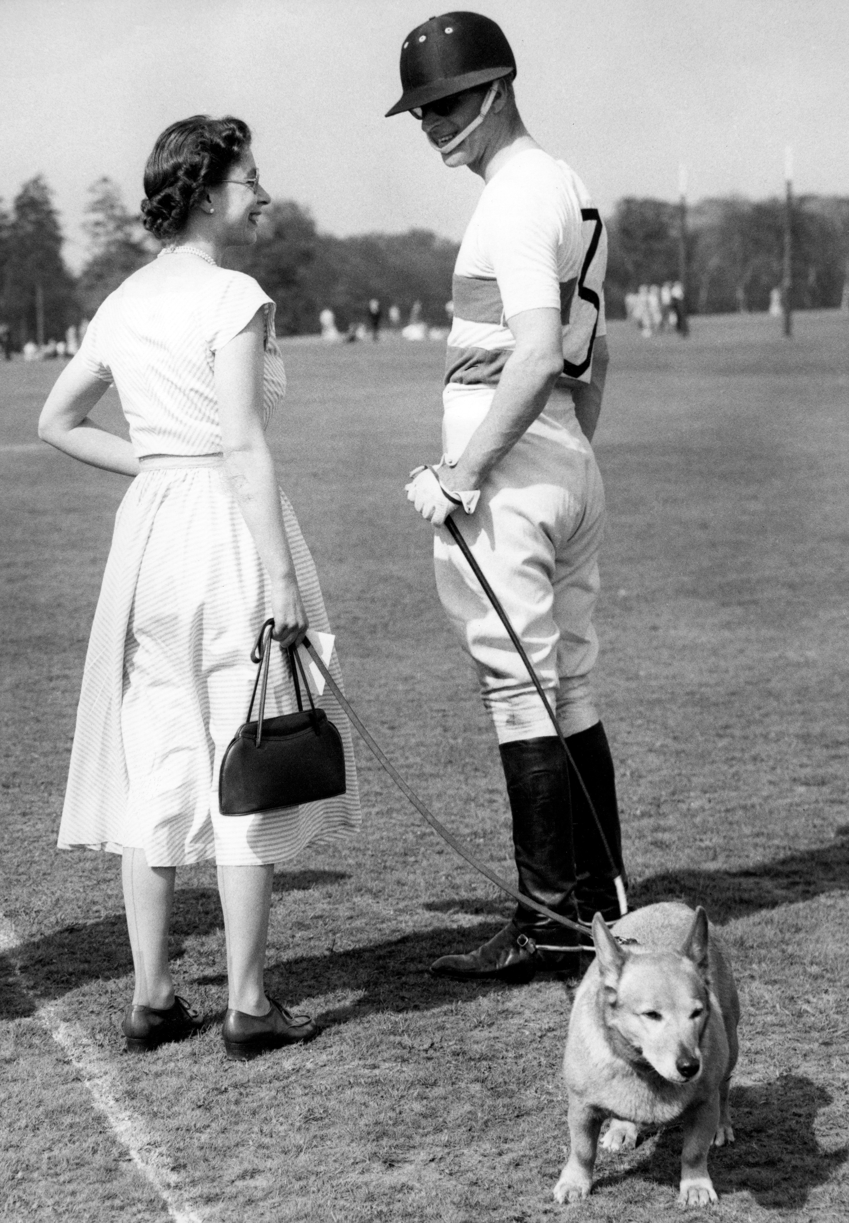 Queen Elizabeth II with one the Royal corgis, chats with polo-playing Prince Philip