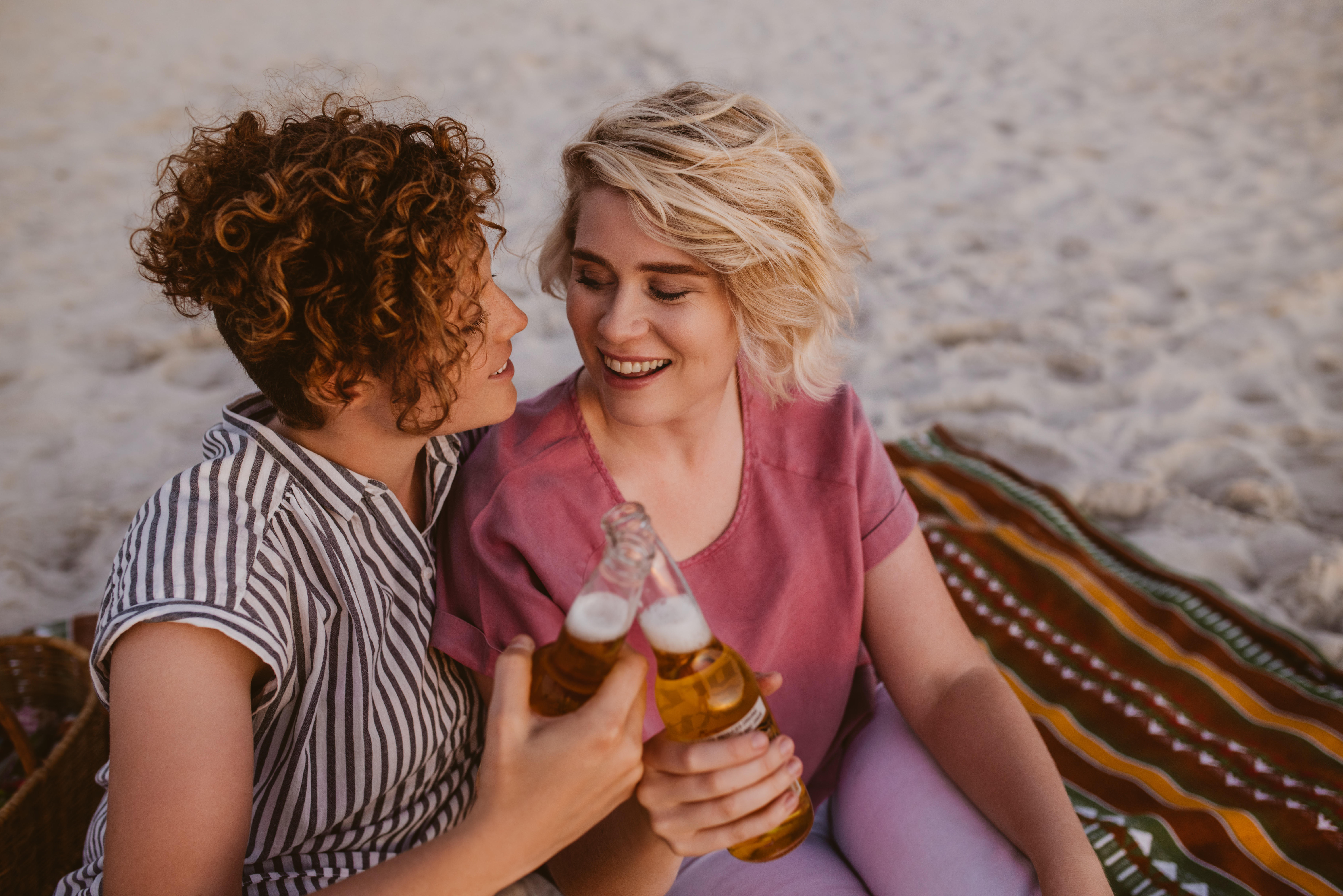 Lesbian couple enjoying beer on a beach