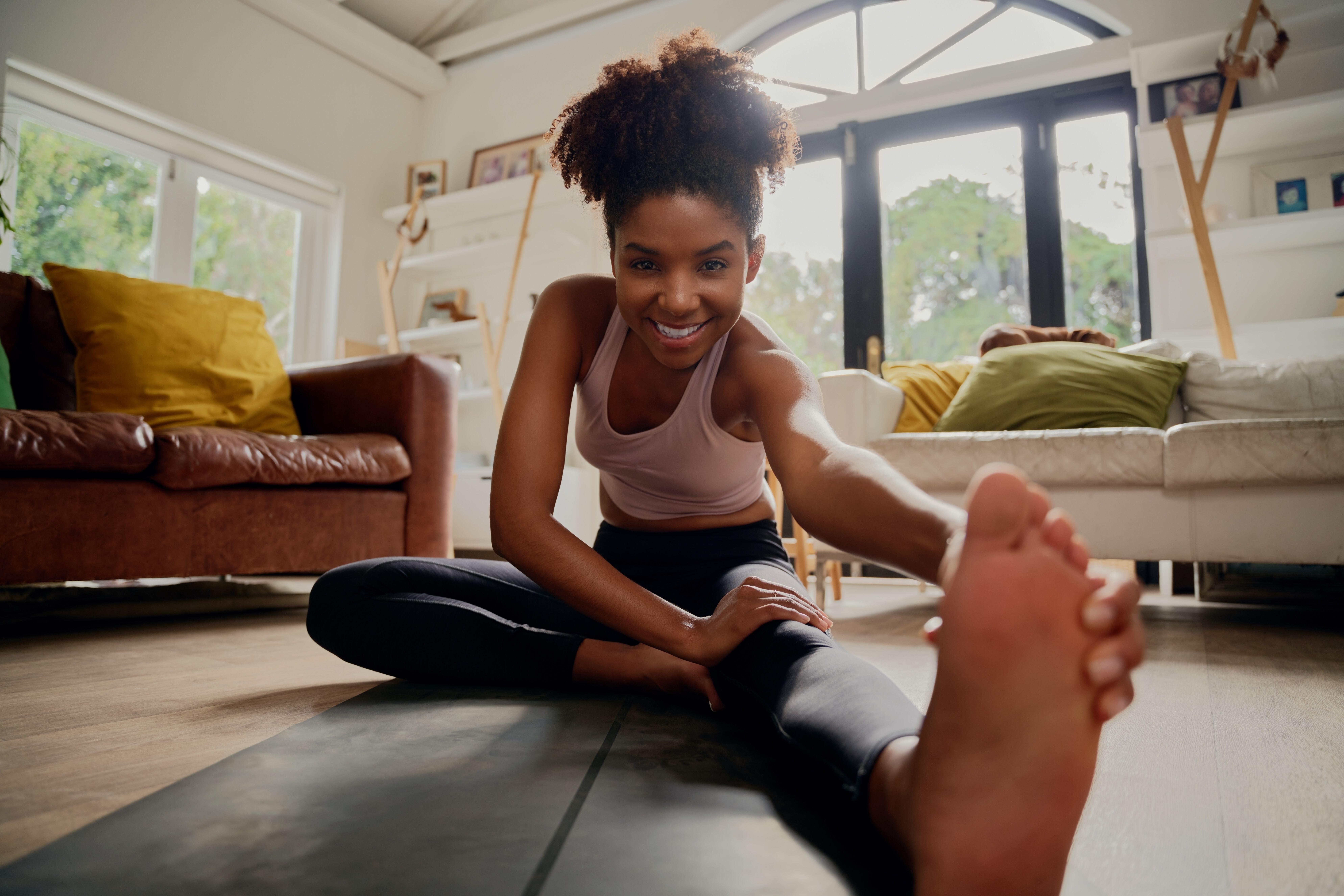 Black woman doing stretches on a mat at home